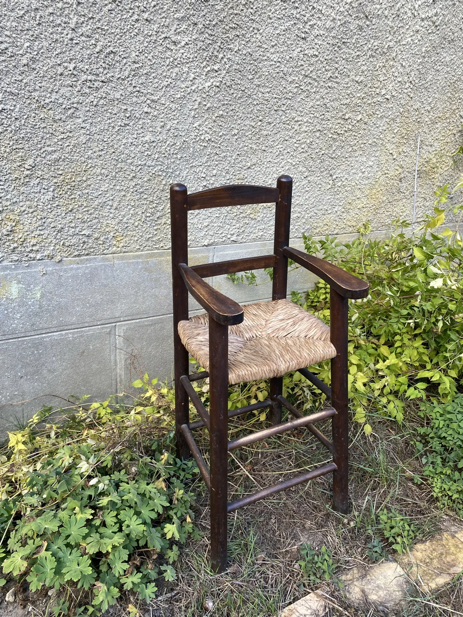 Vintage wooden children's high chair with straw.