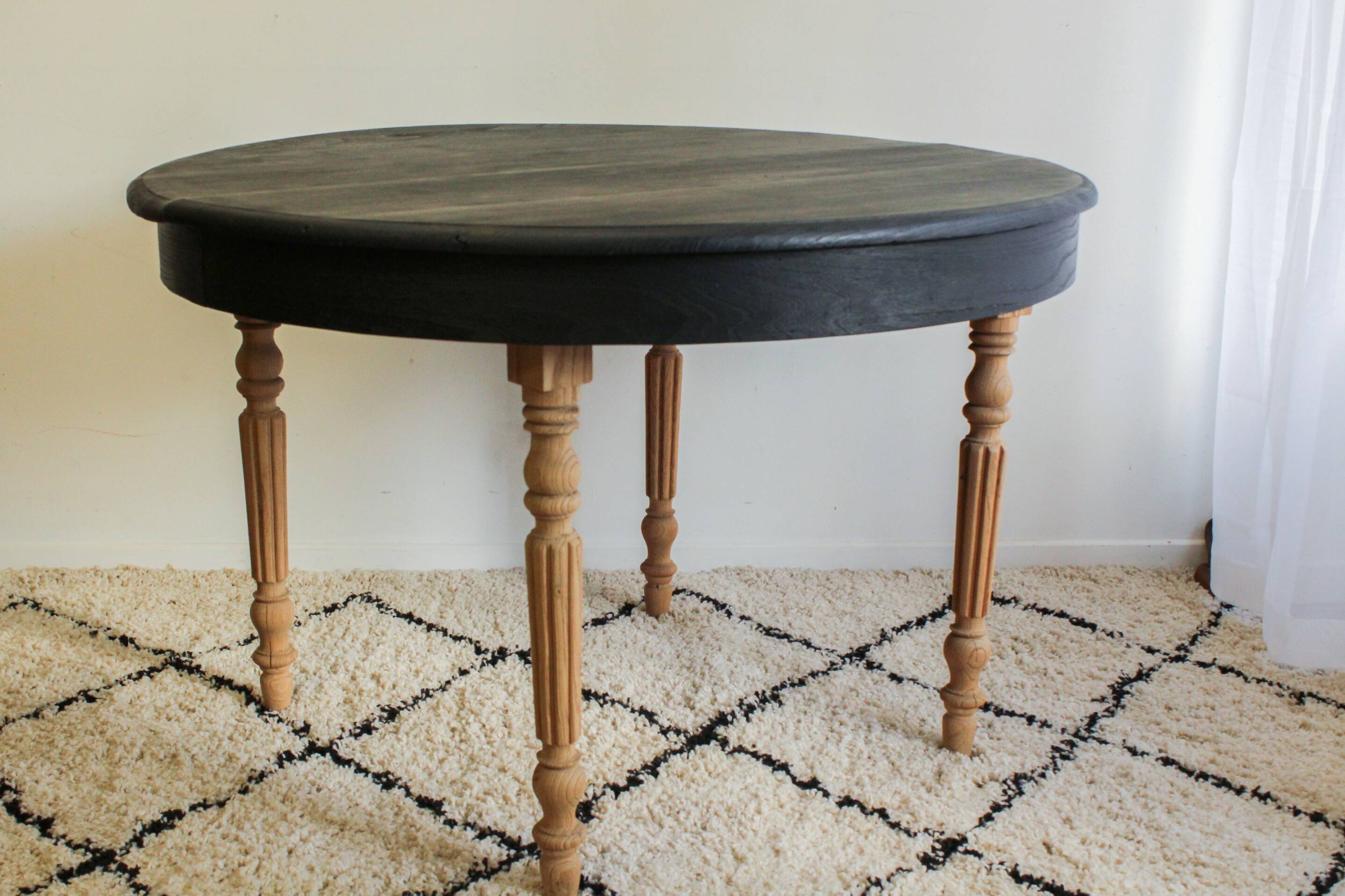 Round black dining table with oak wood.