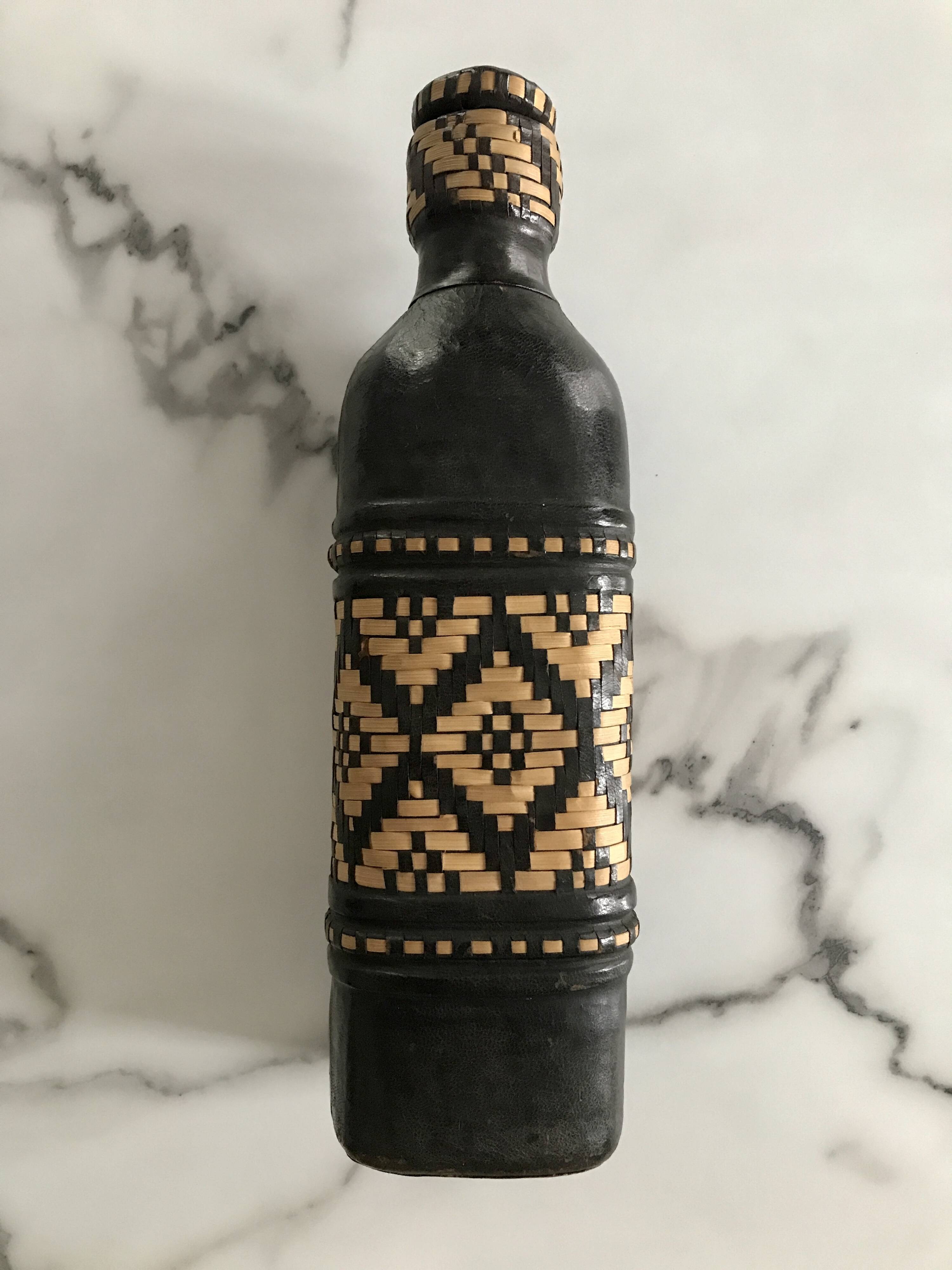 Ethnic decorative bottle in leather and raffia braiding