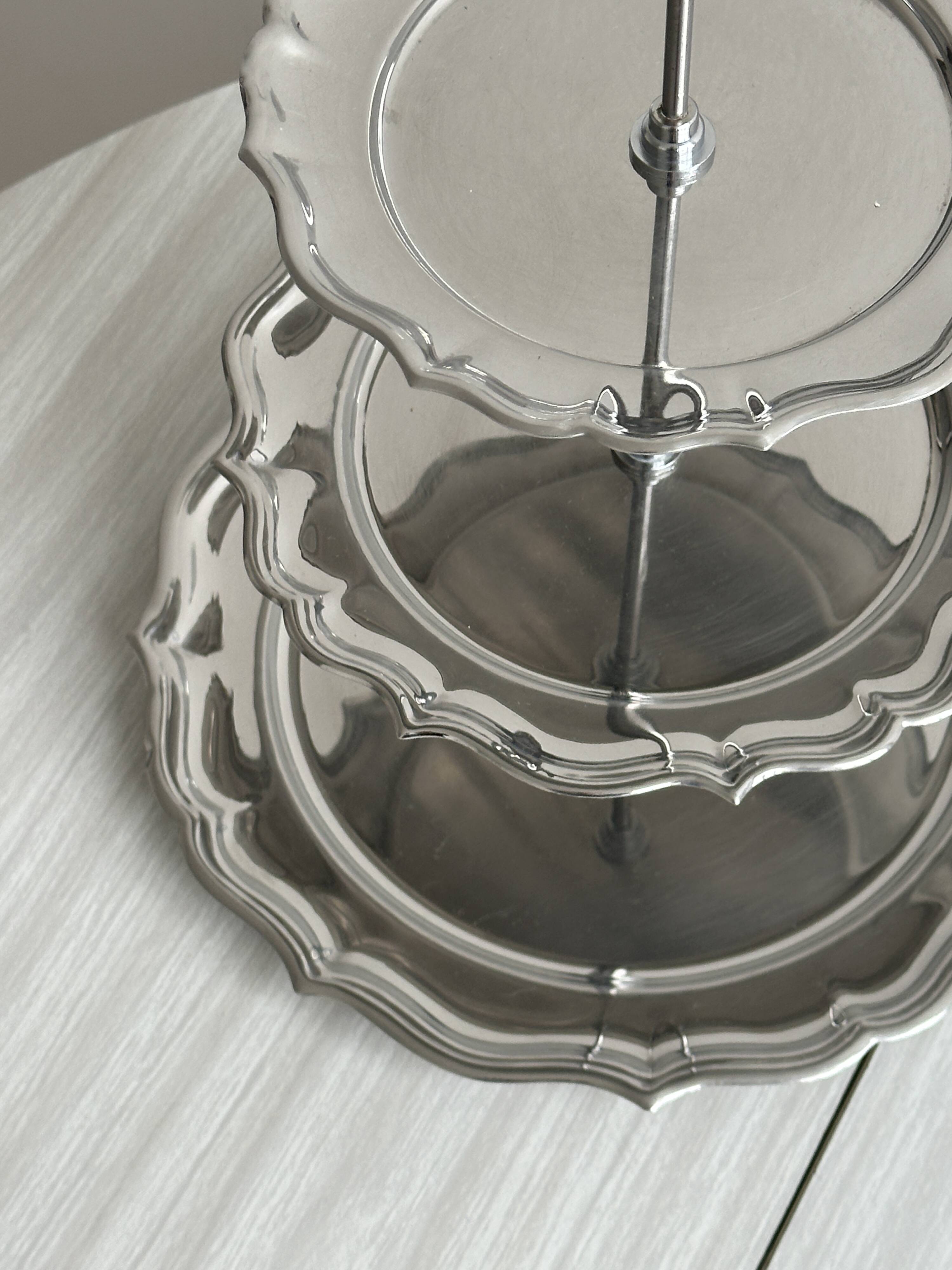 Three-tiered serving trolley in shiny stainless steel.