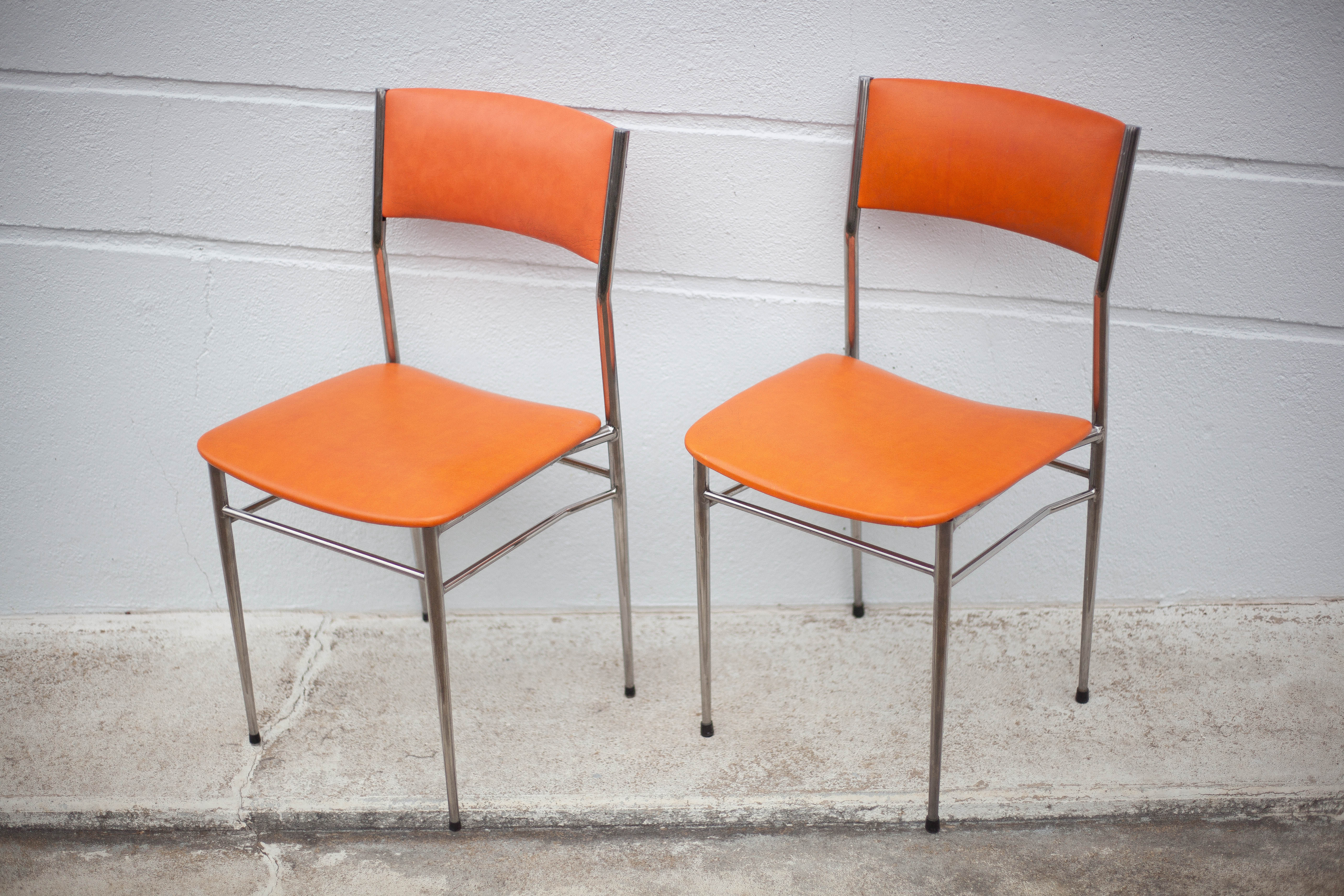Pair of chrome metal chair and orange skai