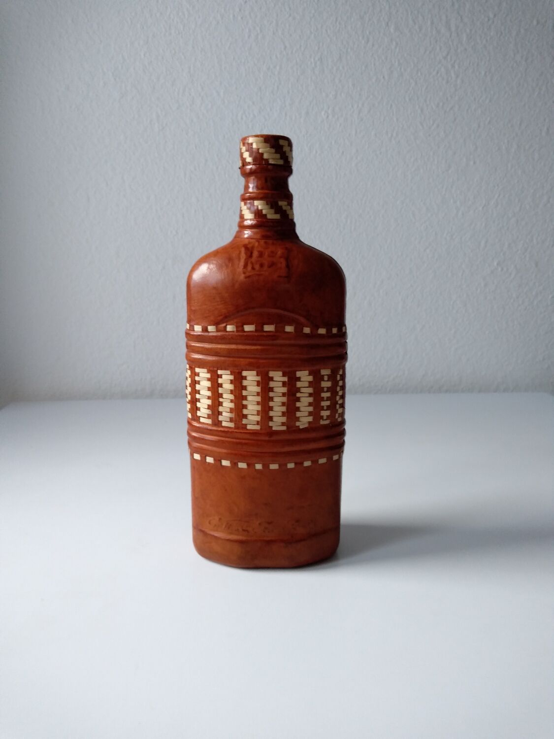 Vintage glass bottle covered with light brown leather and wicker