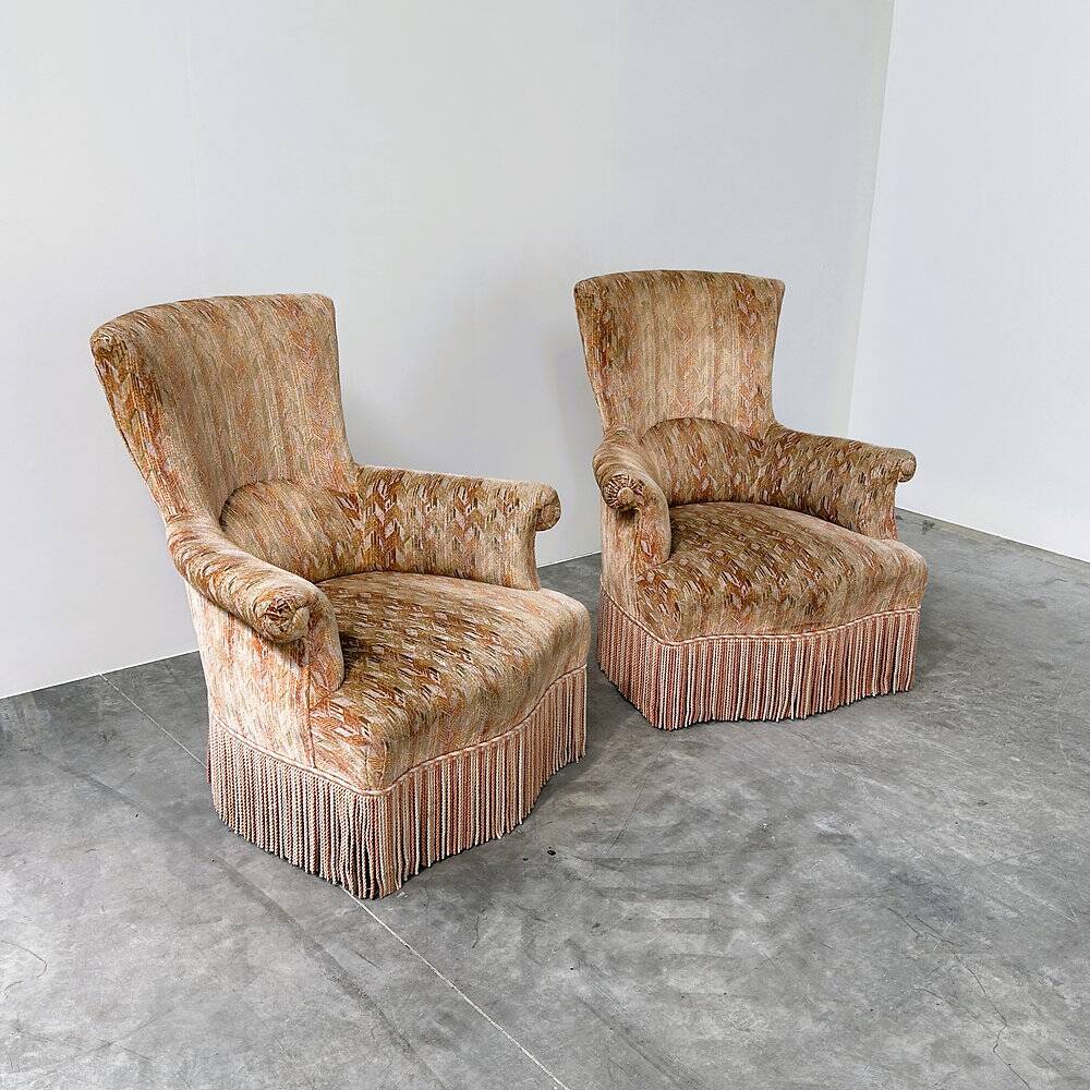 Pair of sculptural Hollywood Regency lounge chairs with original fringed upholstery
