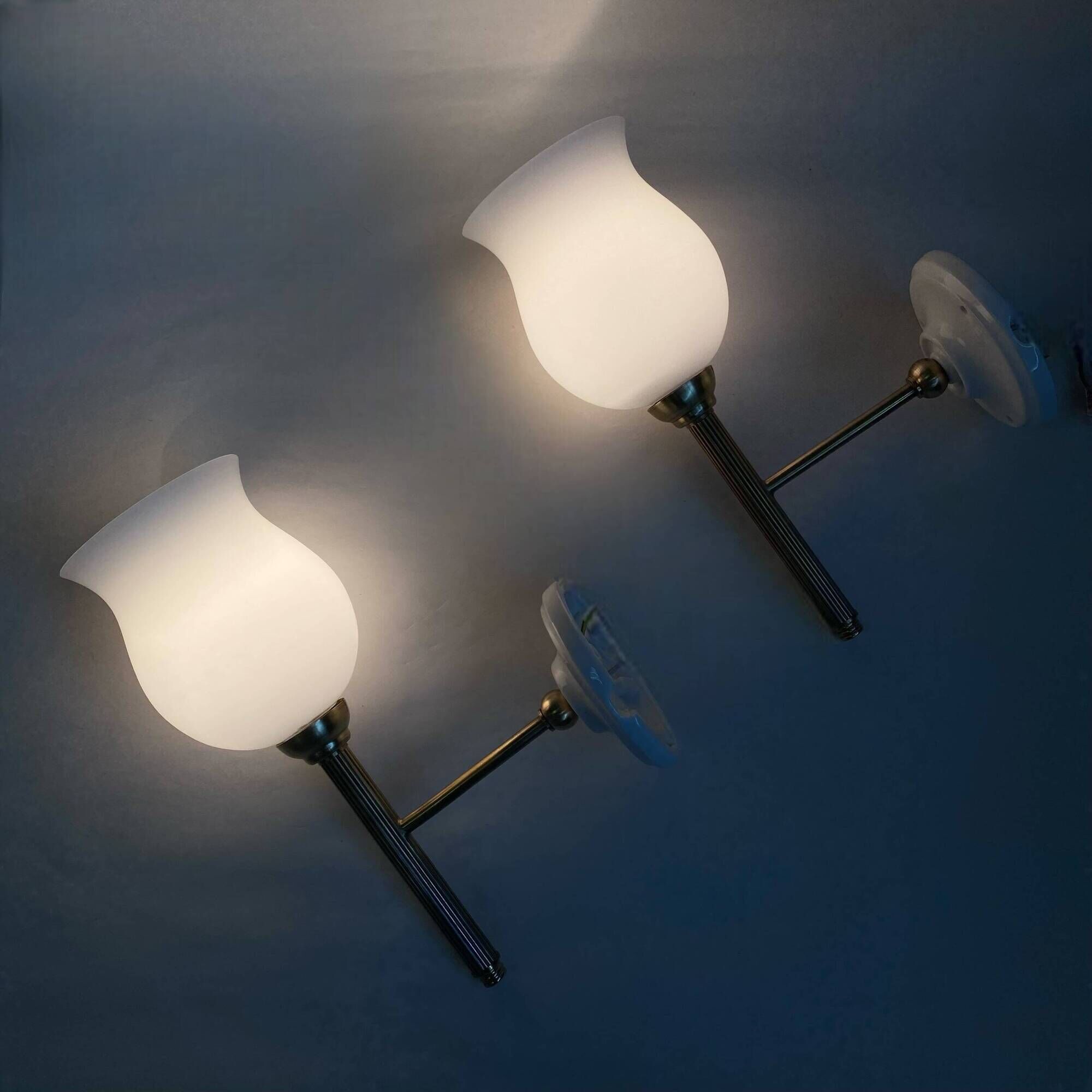 Pair of brass torch wall lights with white opal glass and porcelain