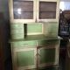 Vintage wooden kitchen cupboard painted green and beige, with glass doors - 1930s
