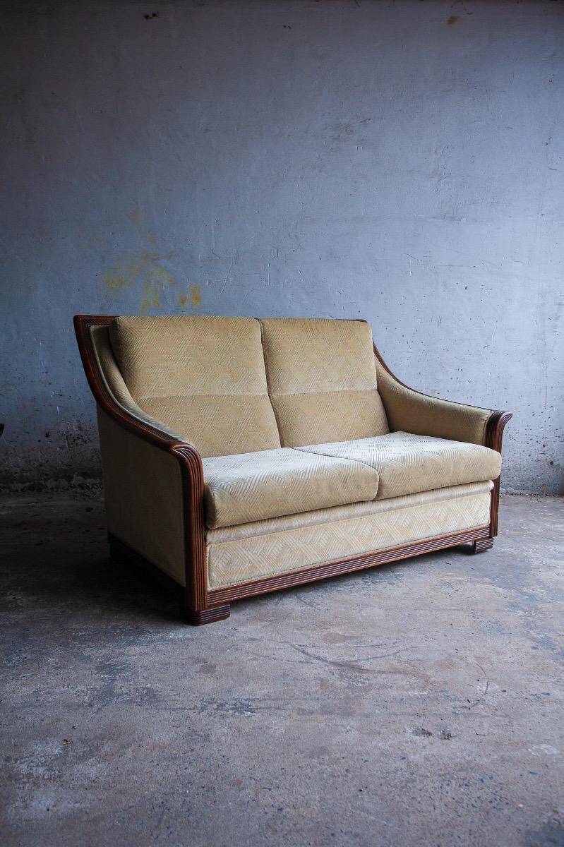 Two-seater Art Deco sofa with ornate wooden details.