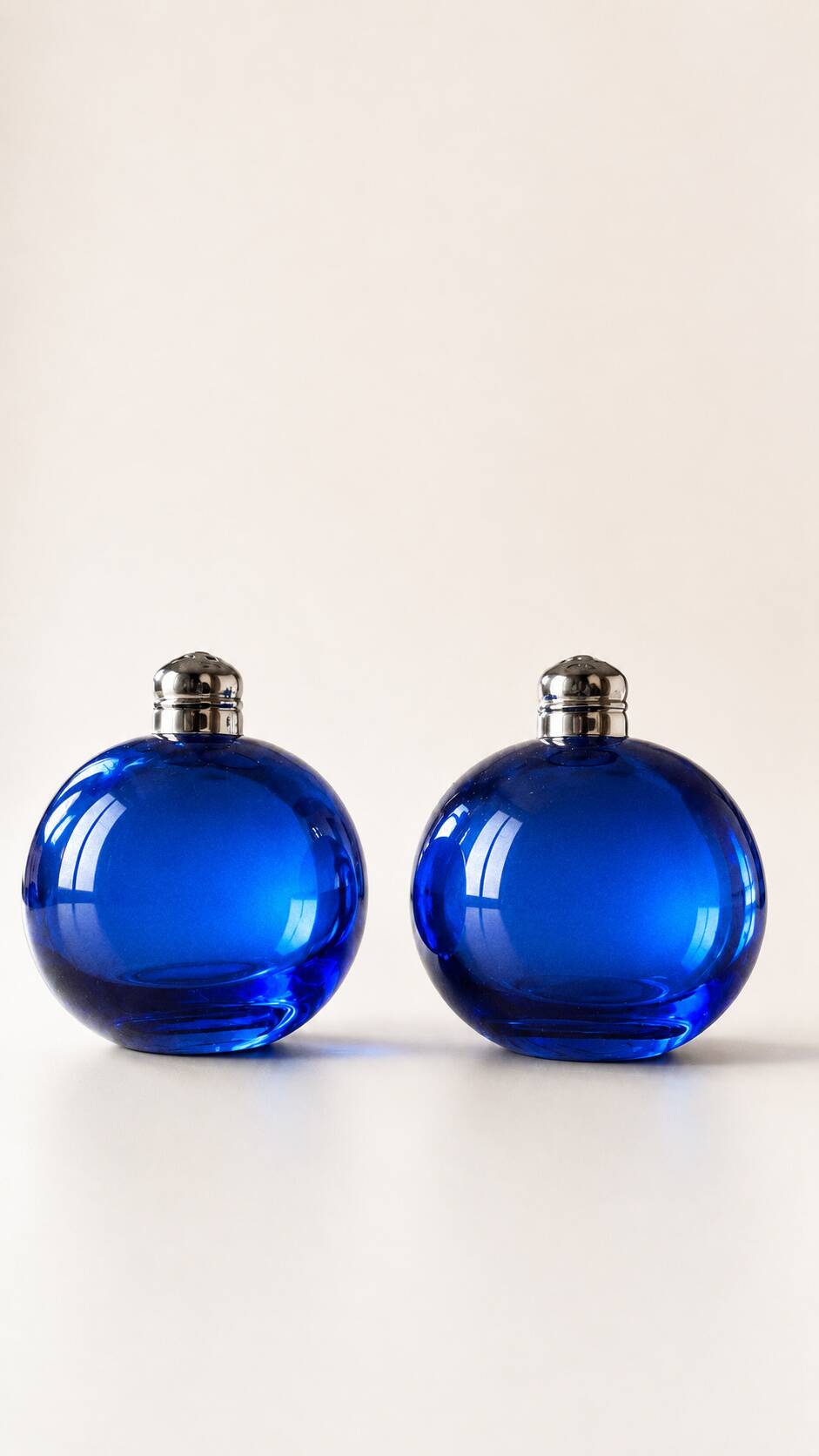 Bright blue glass salt and pepper shakers in a spherical shape.