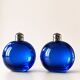 Bright blue glass salt and pepper shakers in a spherical shape.