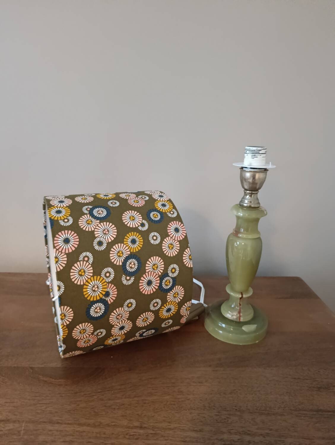 Table lamp with light green onyx base, fabric shade with a khaki background.