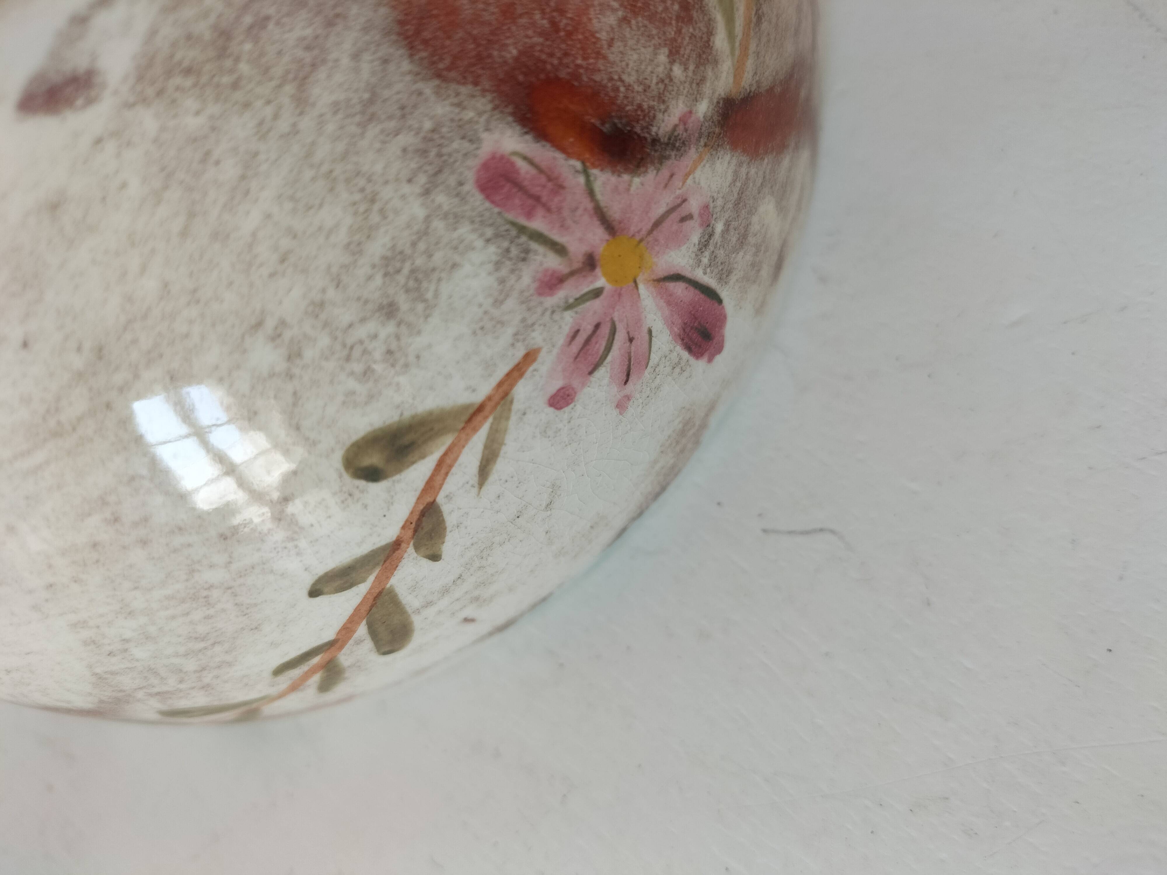 Red-orange glazed ceramic workshop bowl with floral decoration.