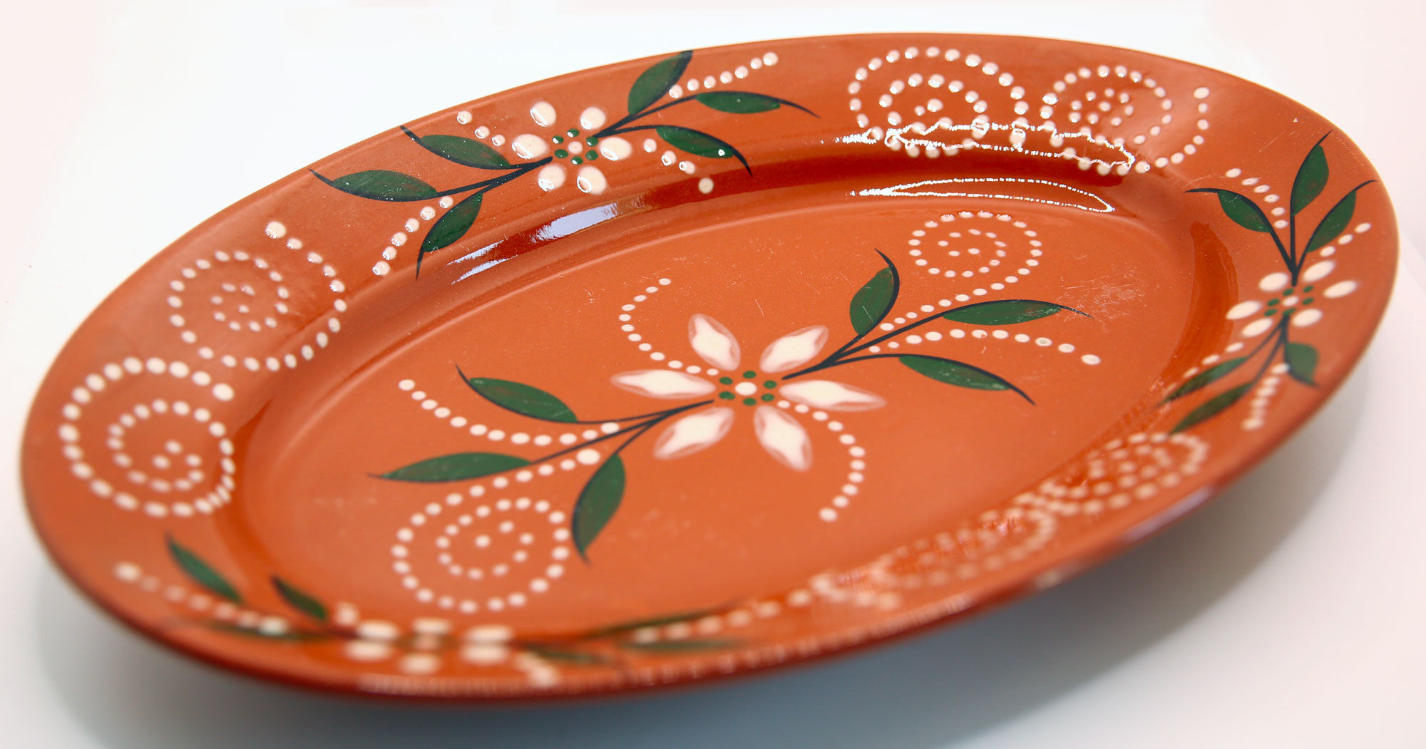 Portuguese XL dish in orange enamelled clay with unbleached flowers and green leaves