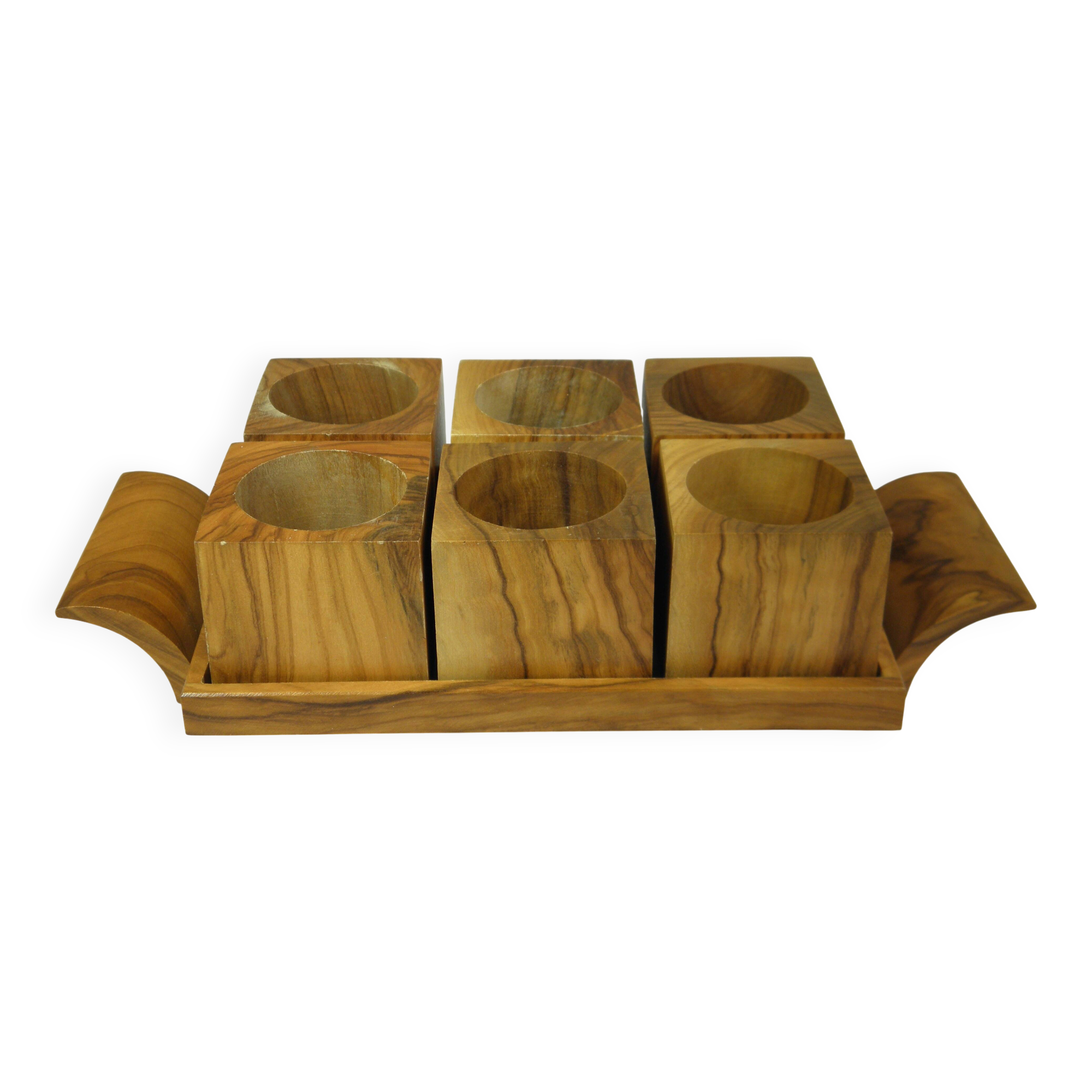 Six egg cups on a wooden tray.