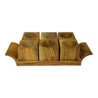 Six egg cups on a wooden tray.