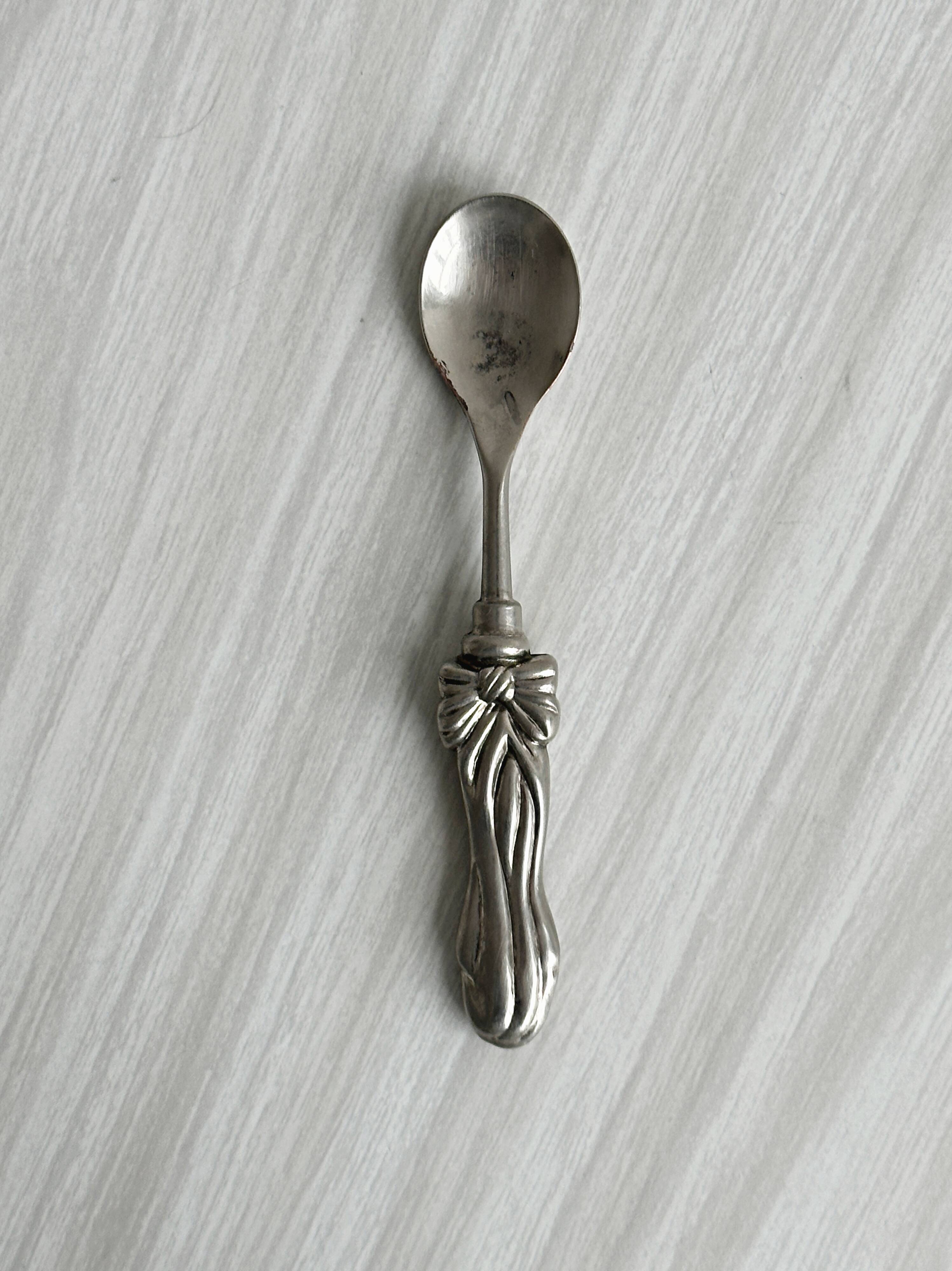 Antique small spoons with a metal bow design