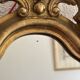 Antique rococo mirror with putti, gilded carved wood and stucco frame, 19th century.
