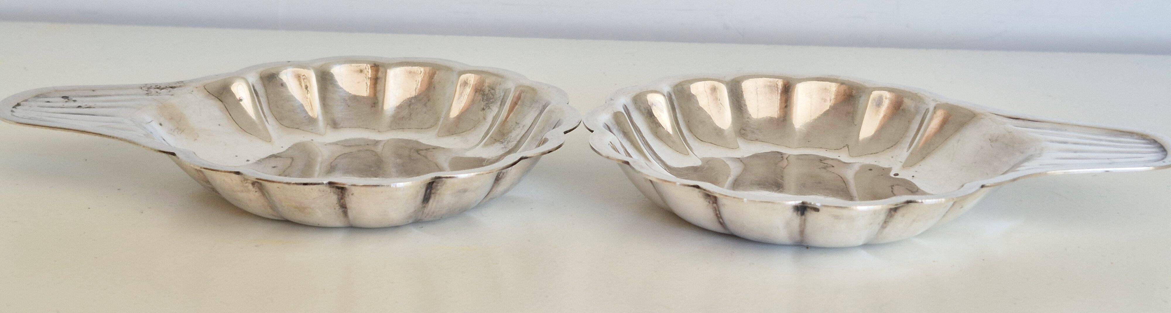 Silver-plated shell-shaped butter dishes, in the shape of a scallop shell.