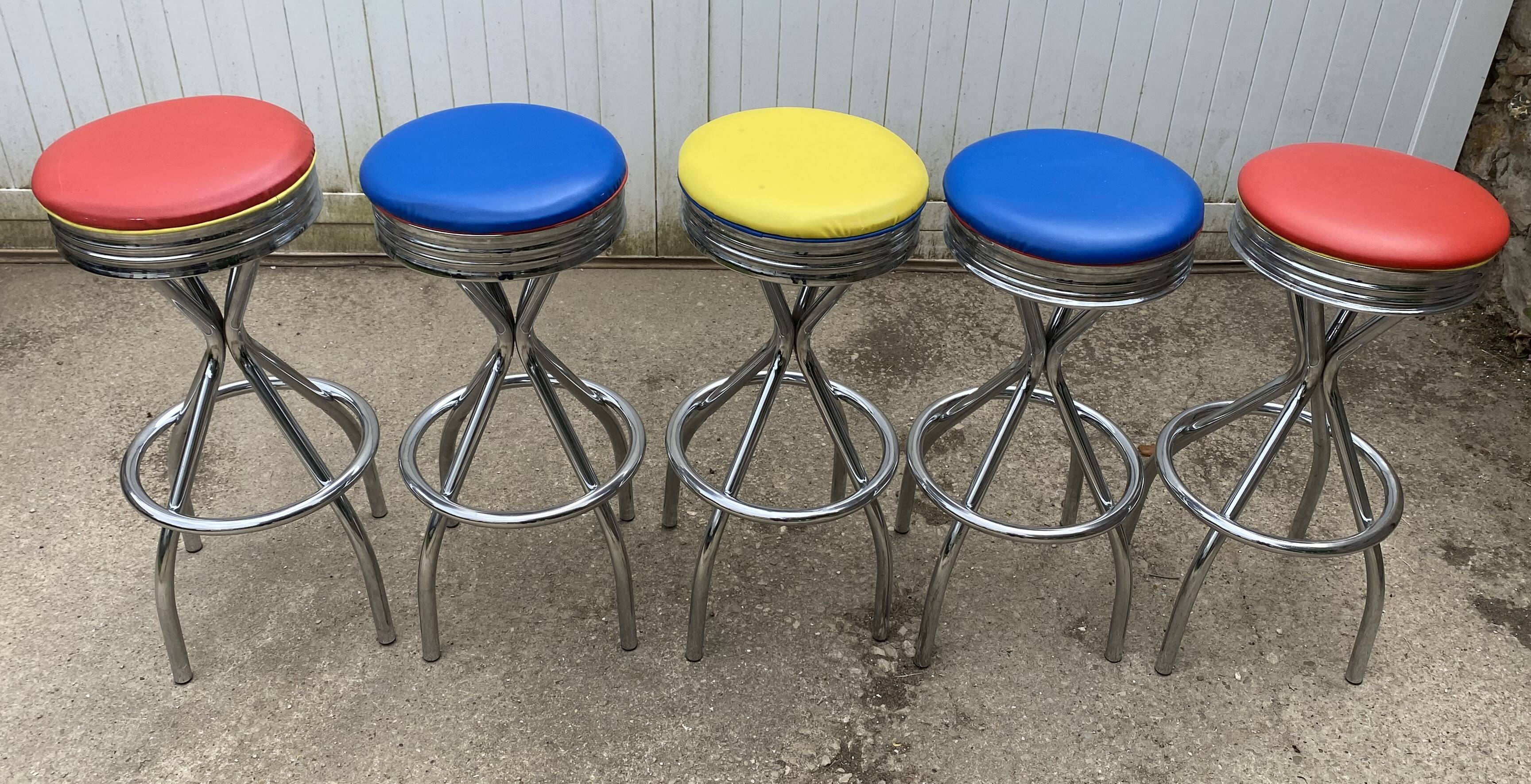Set of 5 vintage swivel bar stools in blue, red, orange, and yellow.