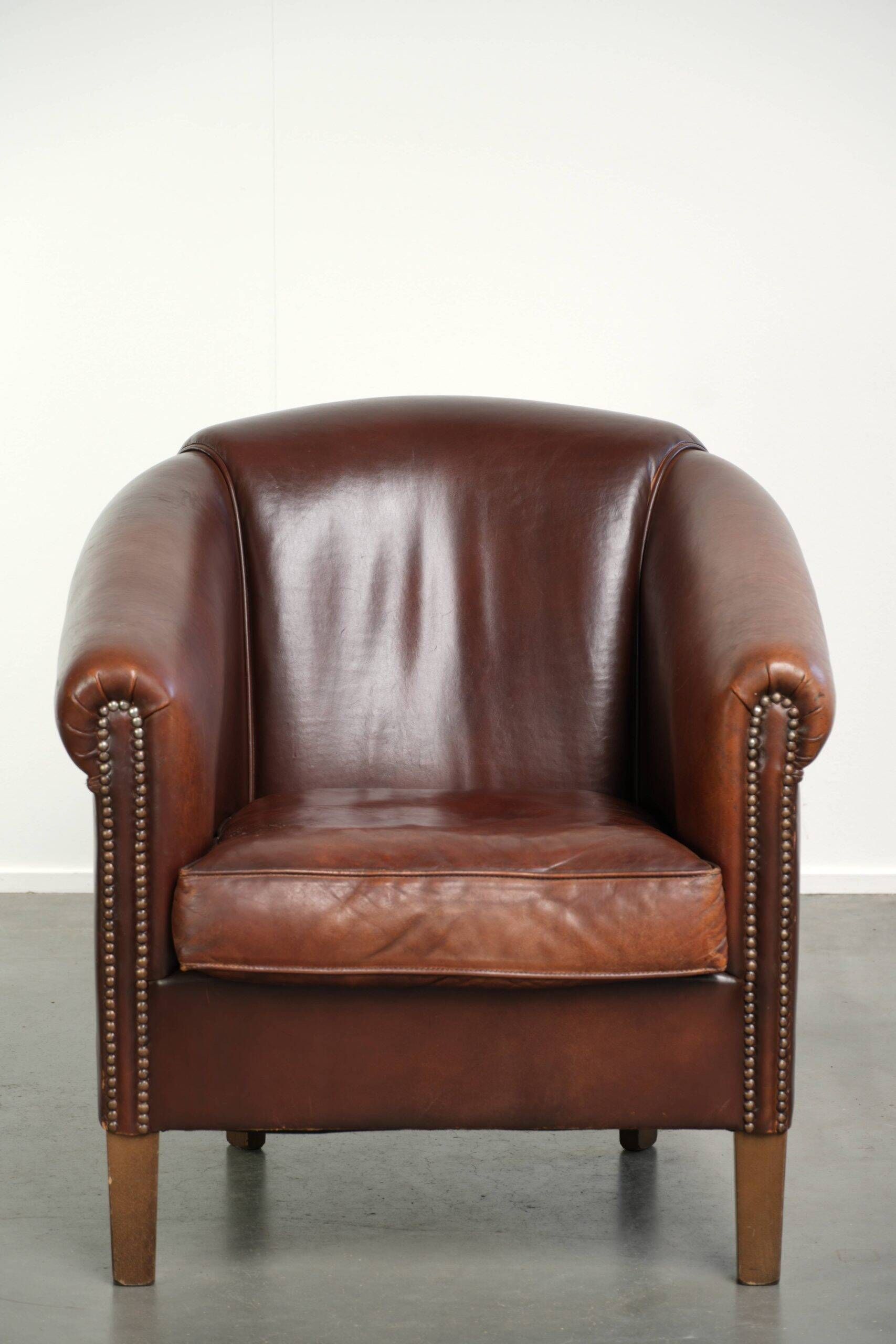 Characterful sheepskin club armchair in a dark cognac colour in English style