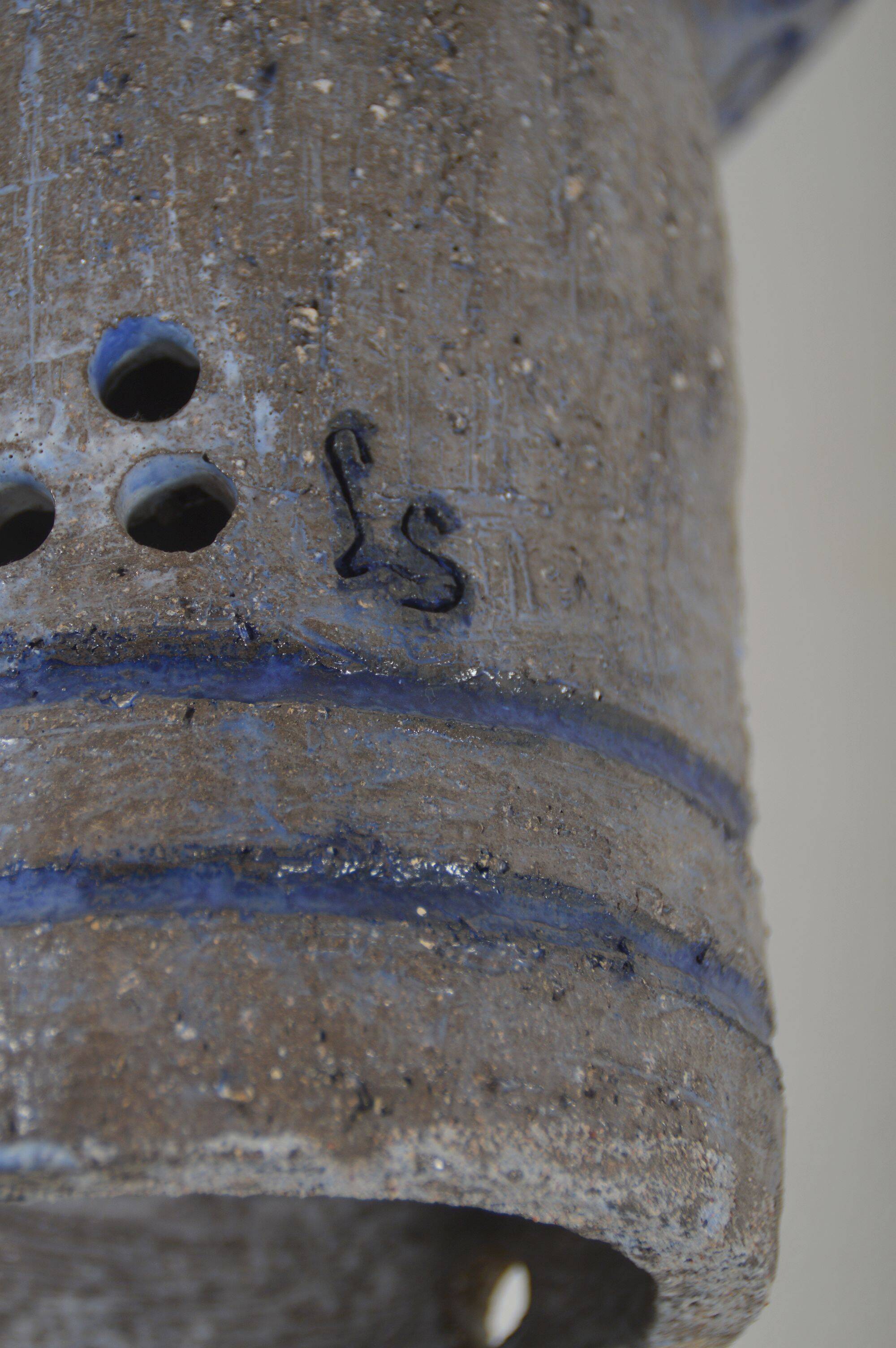Sculpture en céramique avec des motifs circulaires et une signature.