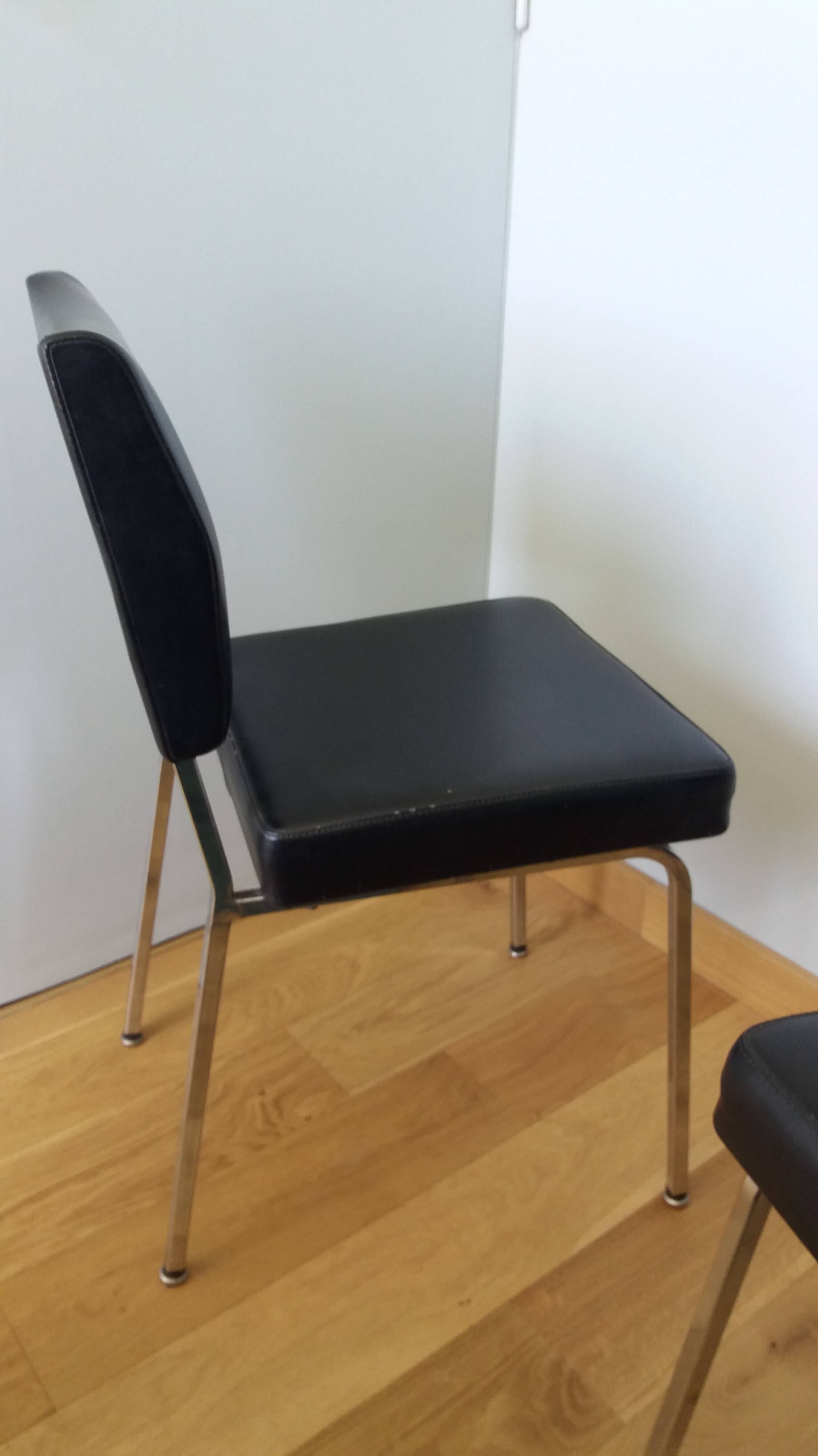 Chrome metal chairs and black faux leather upholstery in retro modernist style.