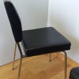 Chrome metal chairs and black faux leather upholstery in retro modernist style.