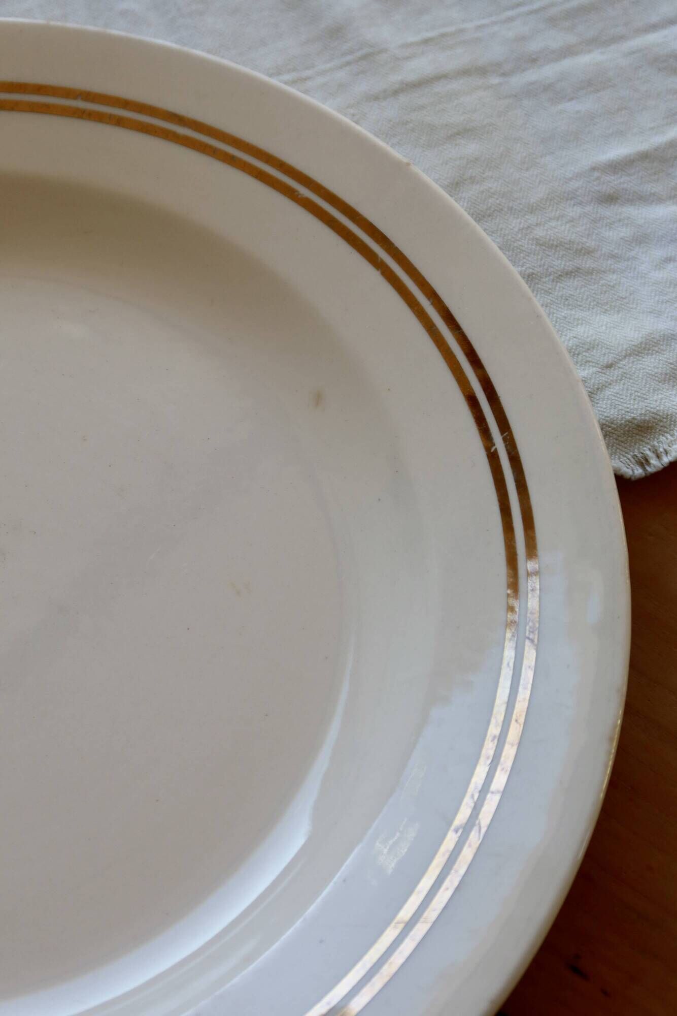 Round vintage ivory earthenware serving dish with double gold trim.