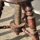 Adjustable brown leather piano stool with turned legs, produced in the 1940s.