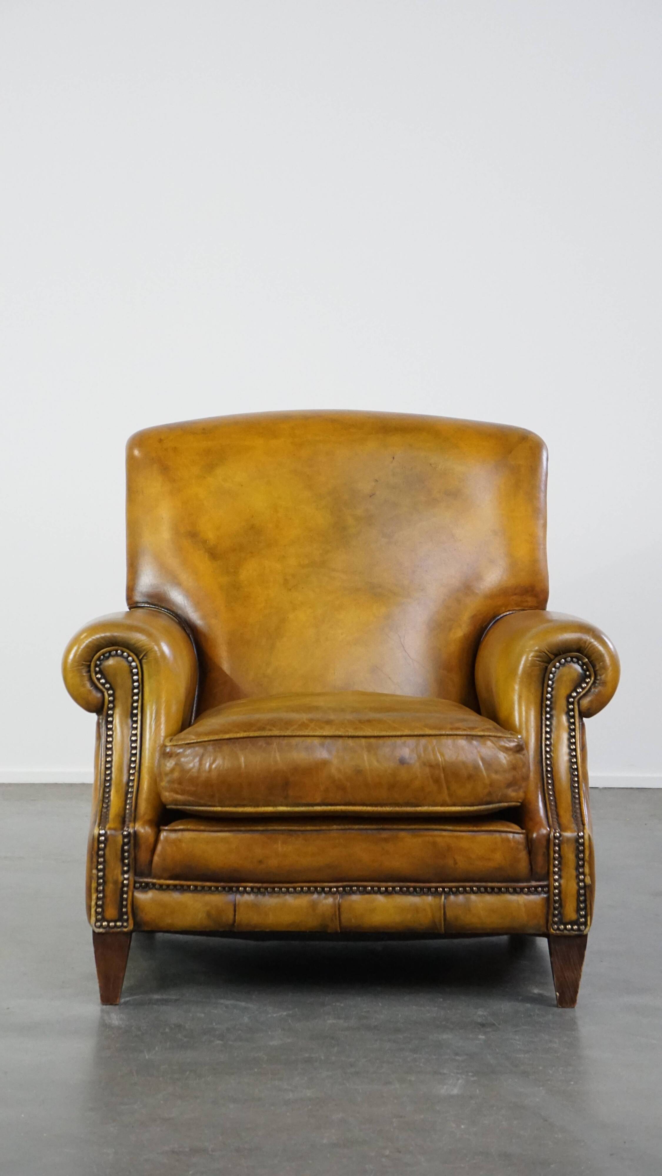 Comfortable large yellow English-style leather armchair with a fine finish and decorative nails