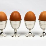 Four silver-plated Christofle egg cups with fluted sides.