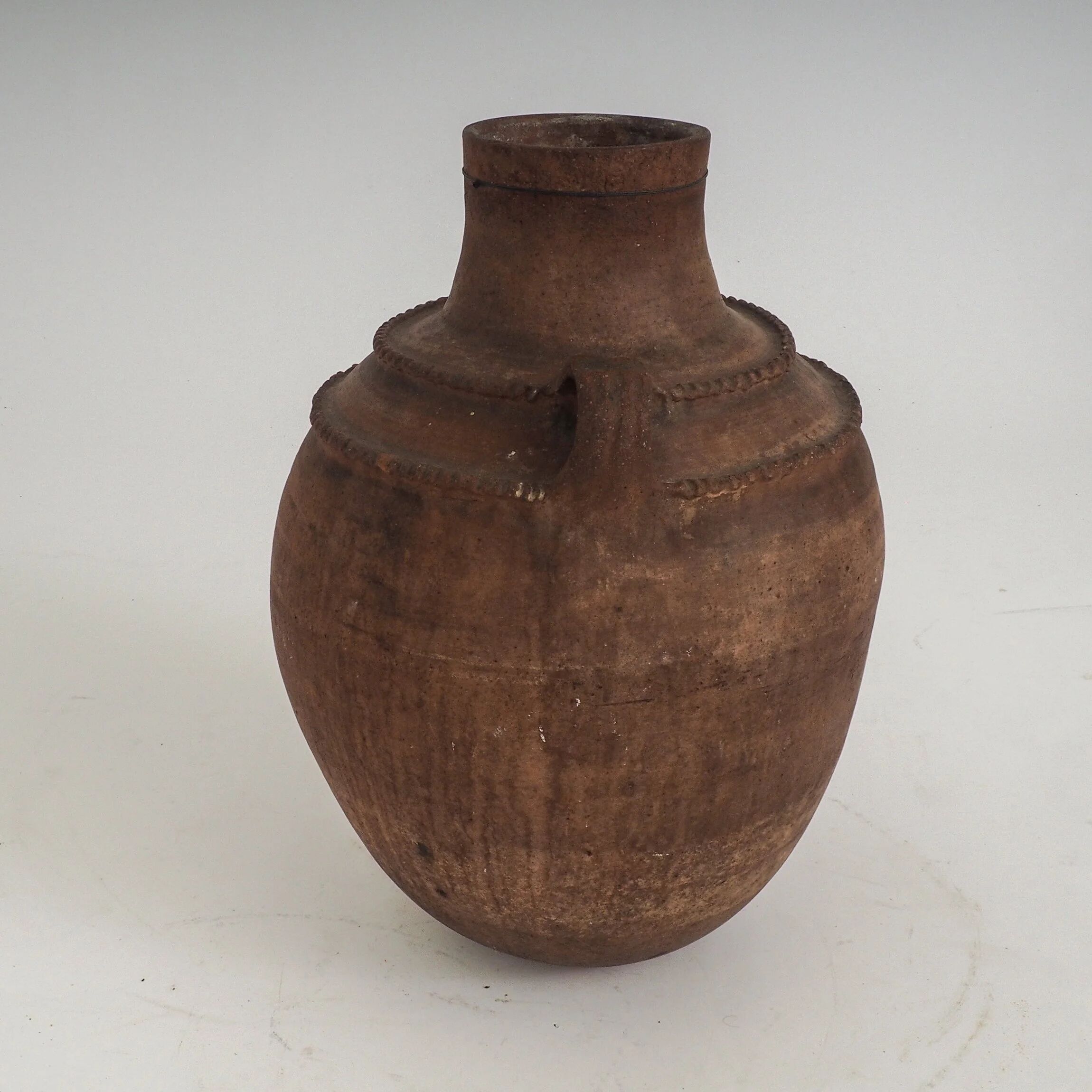 Vaisseau en terre cuite primitive avec des détails géométriques peints à la main.