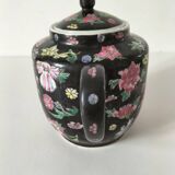 Vintage Chinese teapot with floral polychrome decoration on a black background.