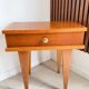 Vintage bedside table with tapered legs.