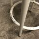 Vintage bar stool in white lace-up, round wooden seat rests circular feet