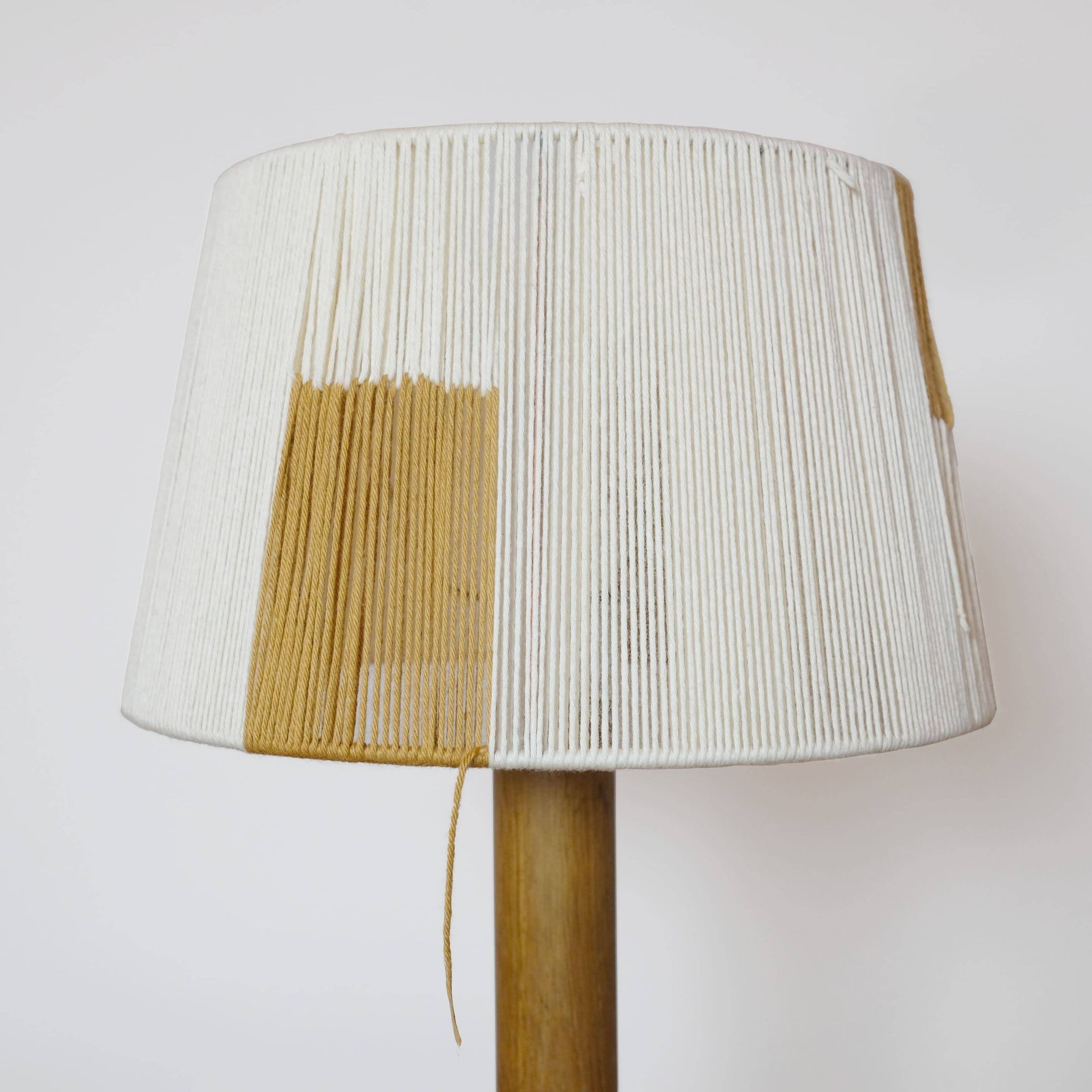 Wooden candle holder mounted as a lamp and its rope shade, 47.5cm.
