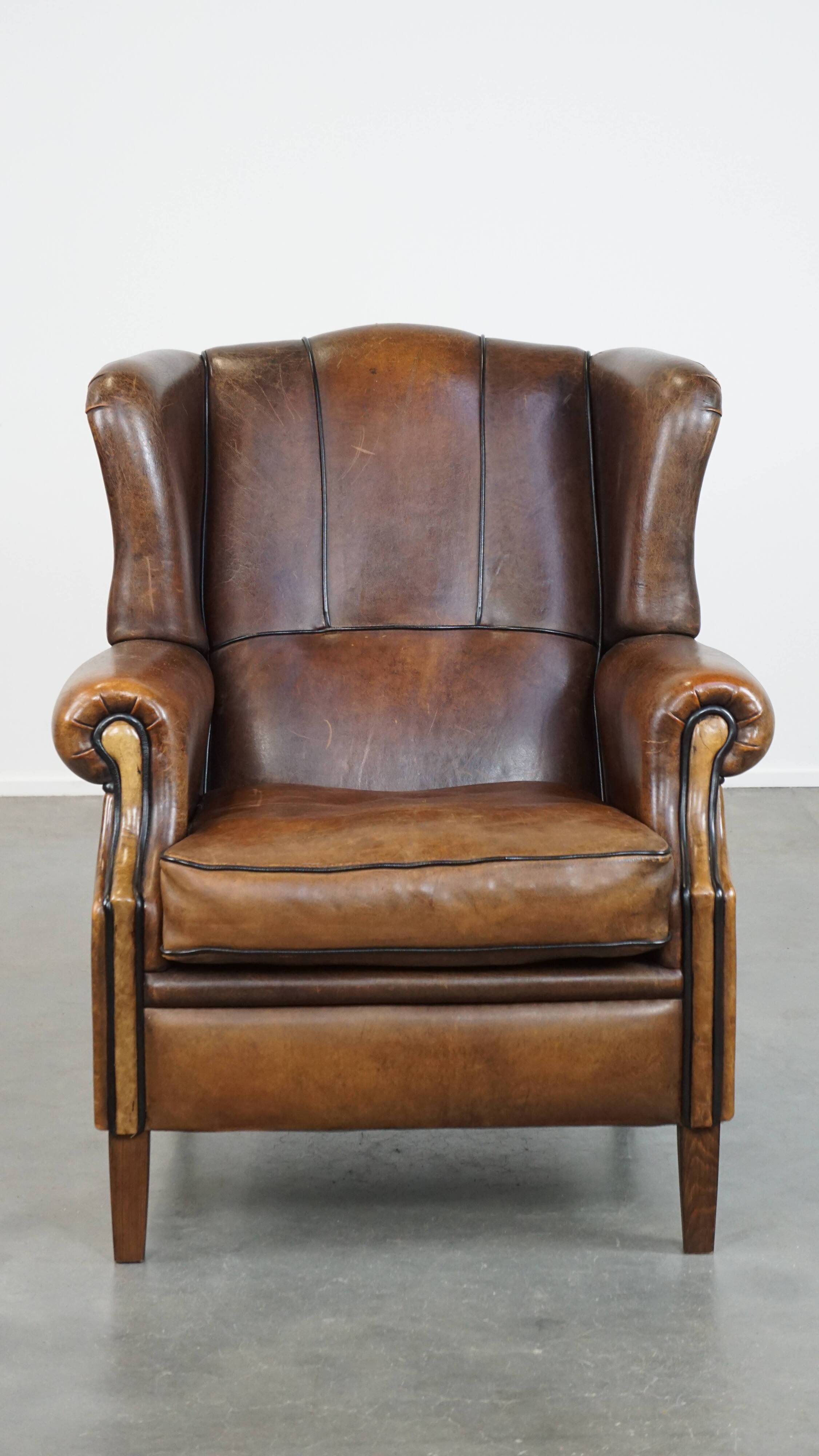 Vintage sheepskin wingback chair finished with black piping