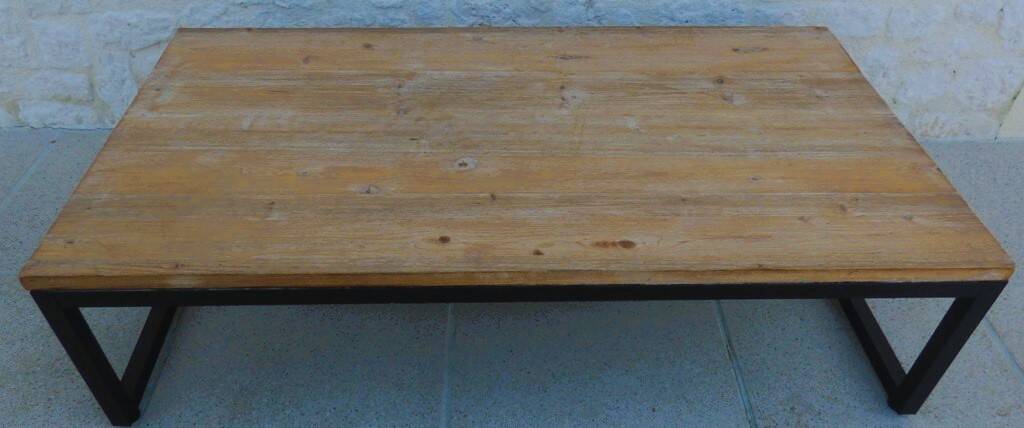 Industrial style coffee table with wooden top supported by a metal base -