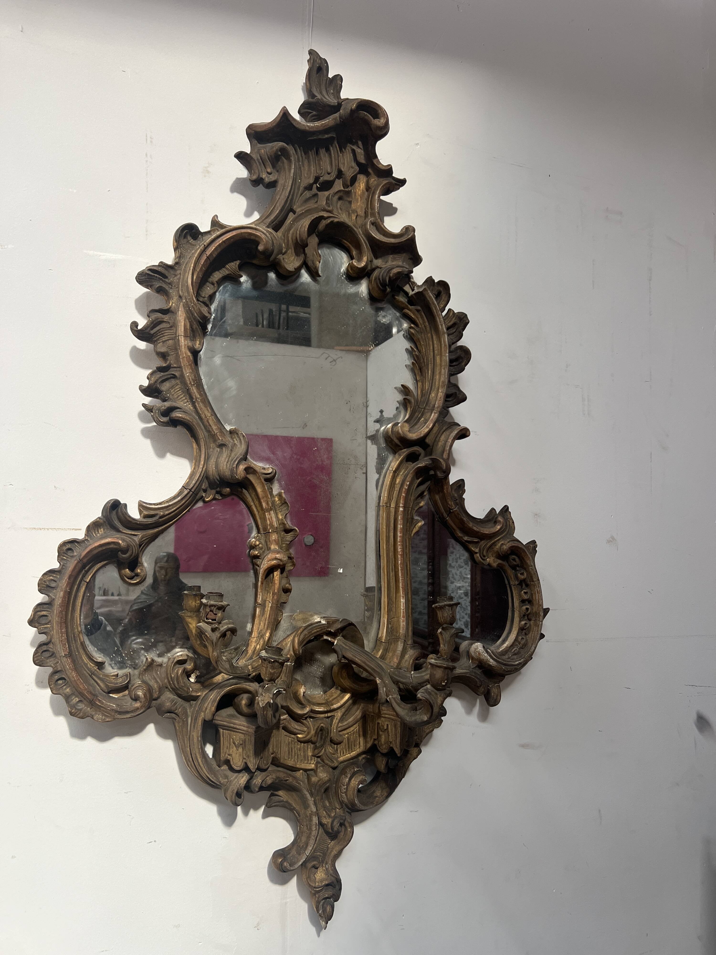 Mirror with a decorative frame featuring a four-light wall sconce, 19th century.