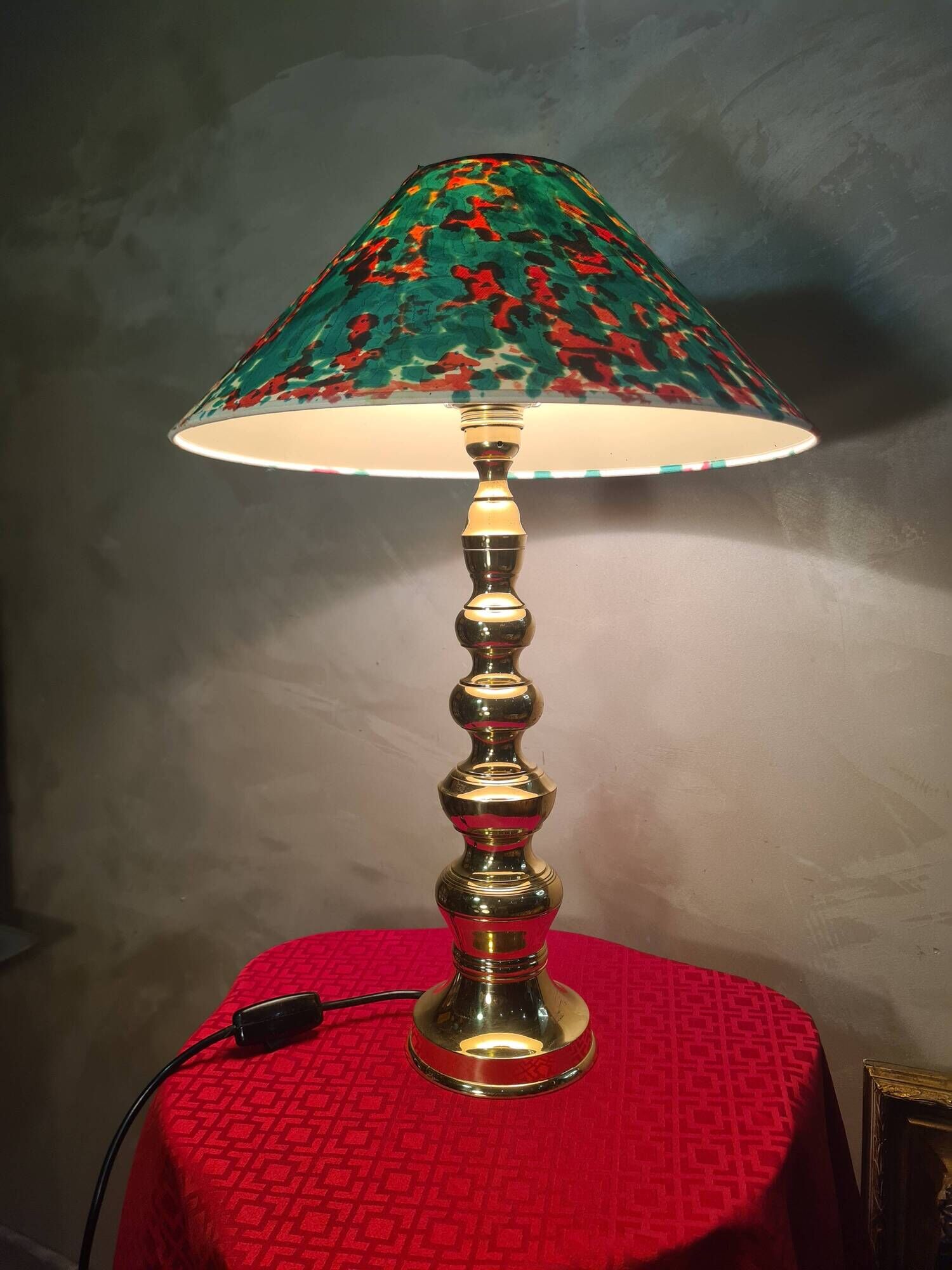 This elegant table lamp features a sculptural base in shiny gold brass.