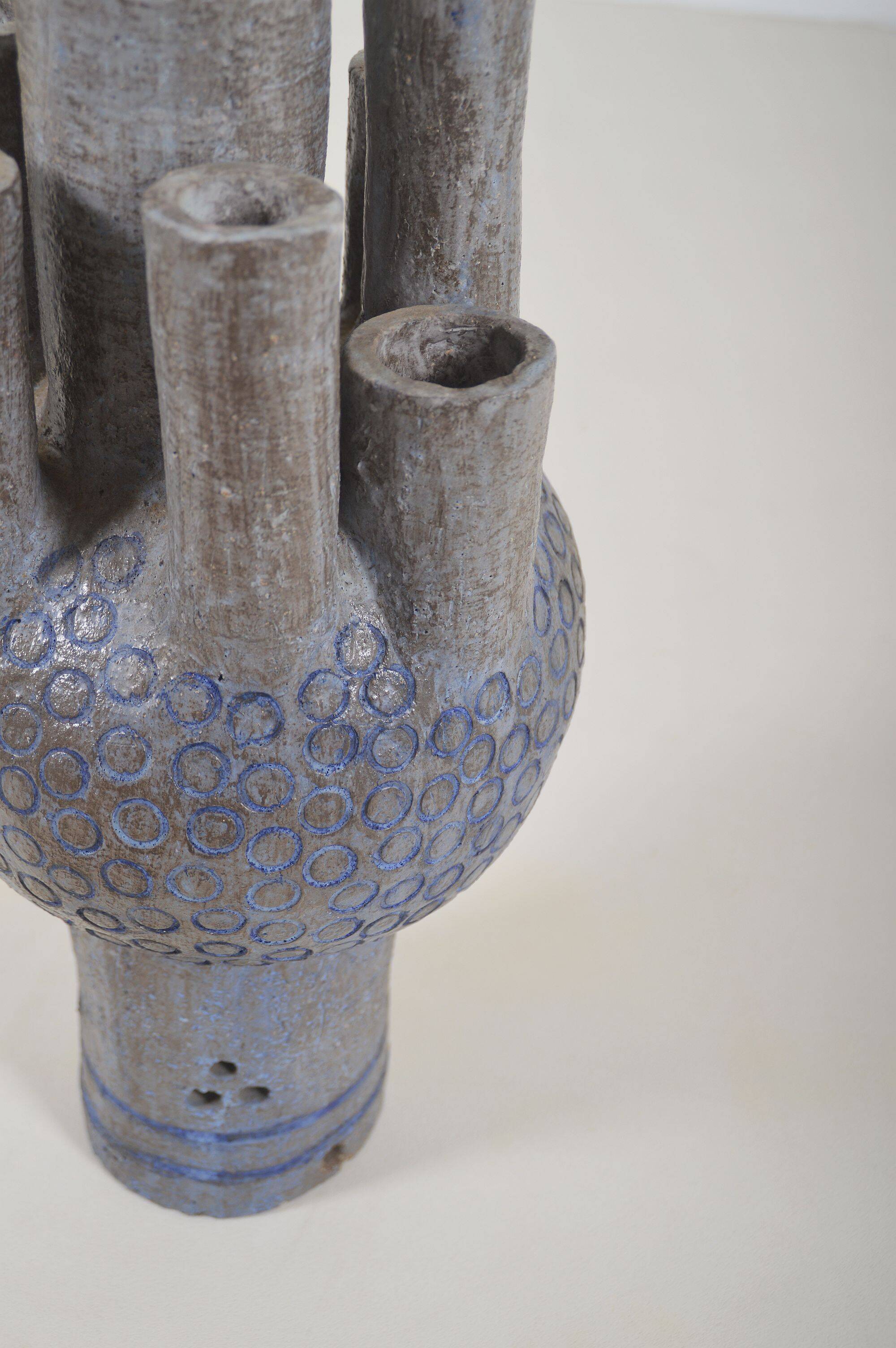 Sculpture en céramique avec des motifs circulaires et une signature.