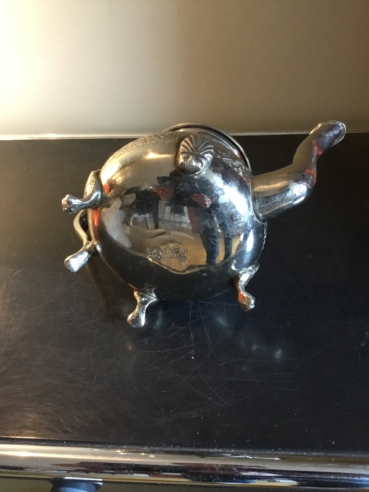Traditional metal teapot with silver plating, Eastern style, on a stand.