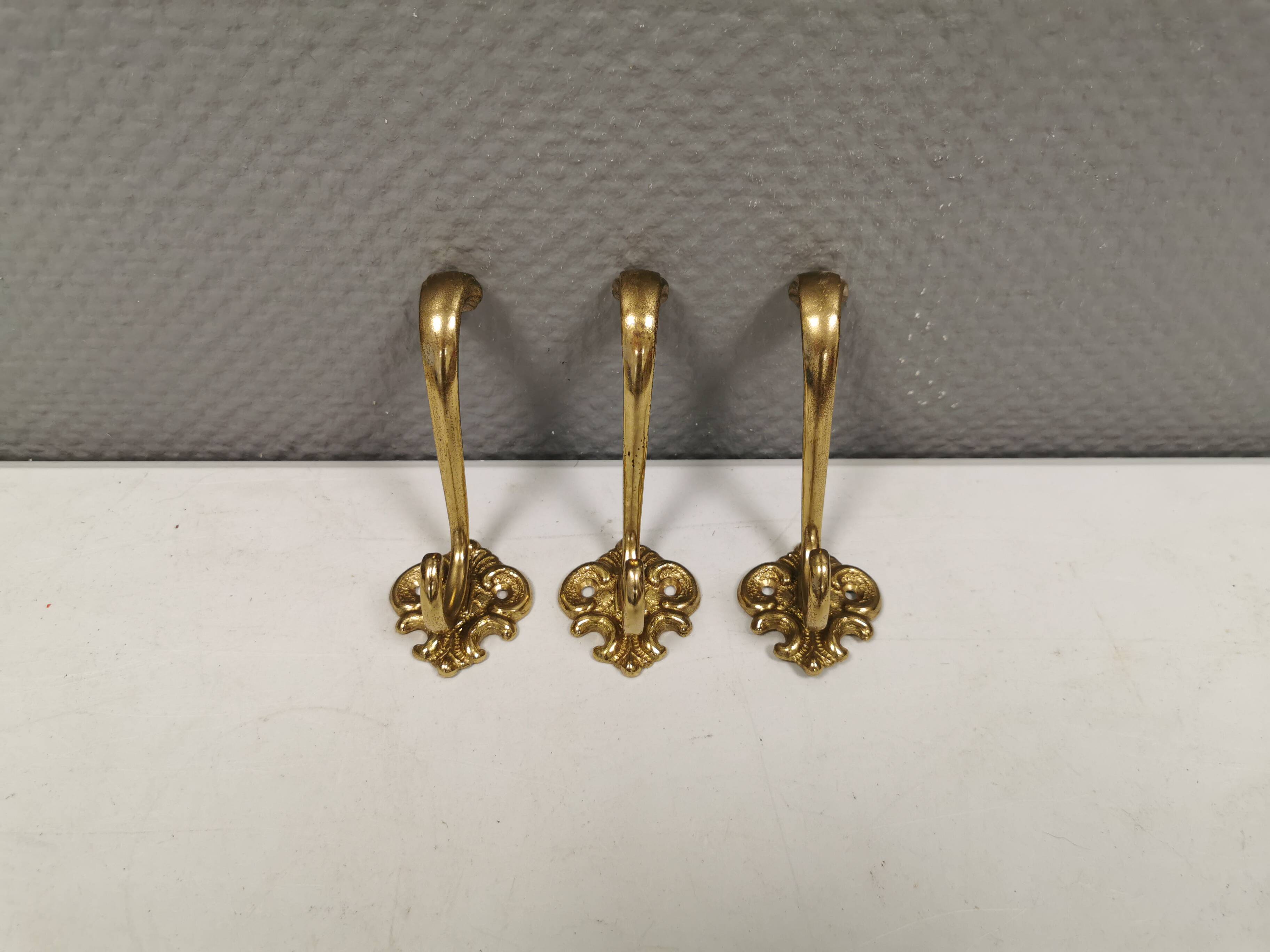 Three old and beautiful brass hooks with decorative motifs