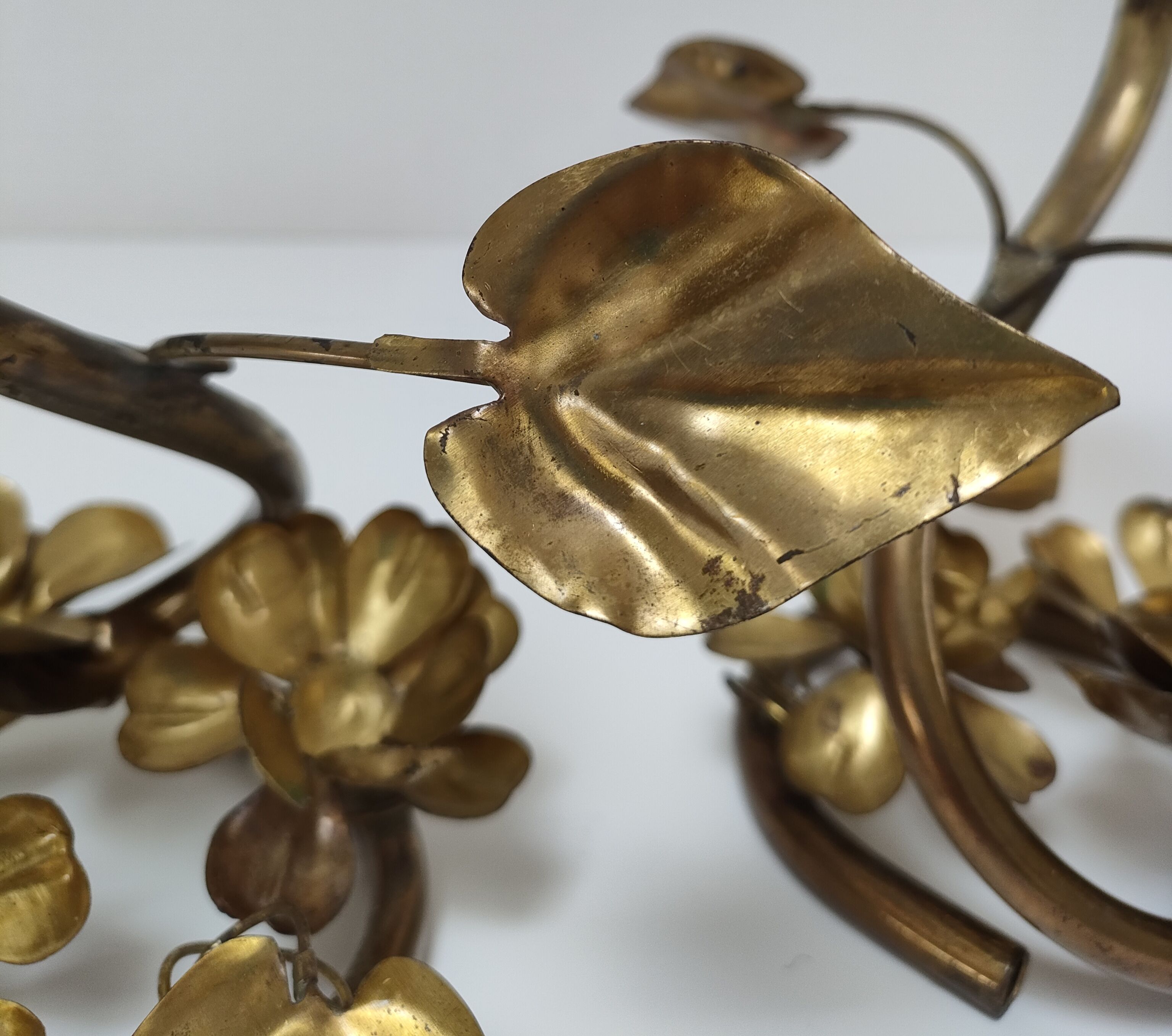 Pair of brass candle holders decorated with patinated metal flowers