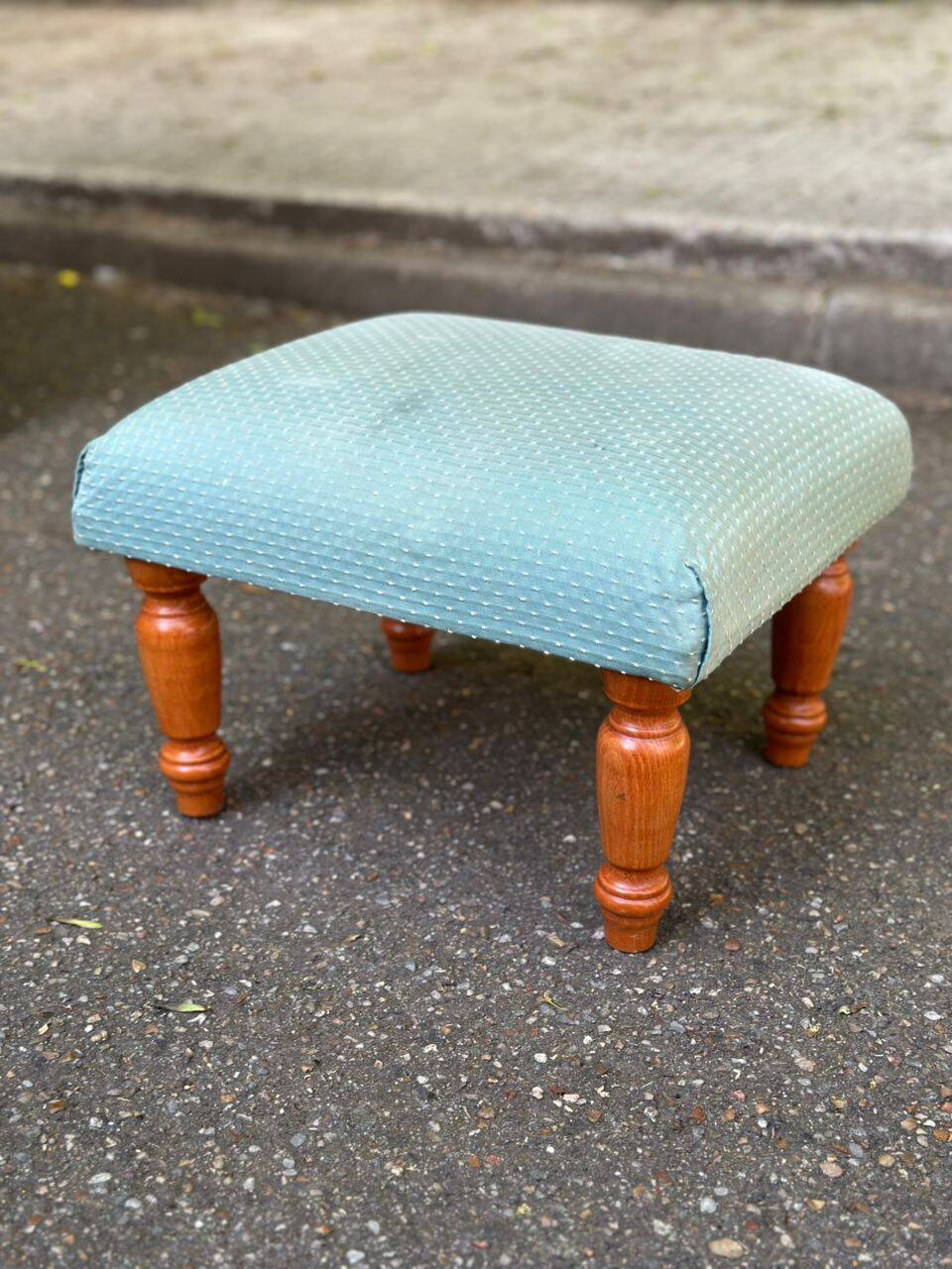 Vintage footstool made of solid wood and blue fabric.