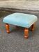 Vintage footstool made of solid wood and blue fabric.