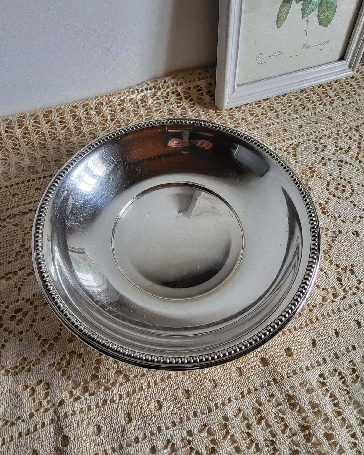 Shallow round metal plate with pearl bead decoration.