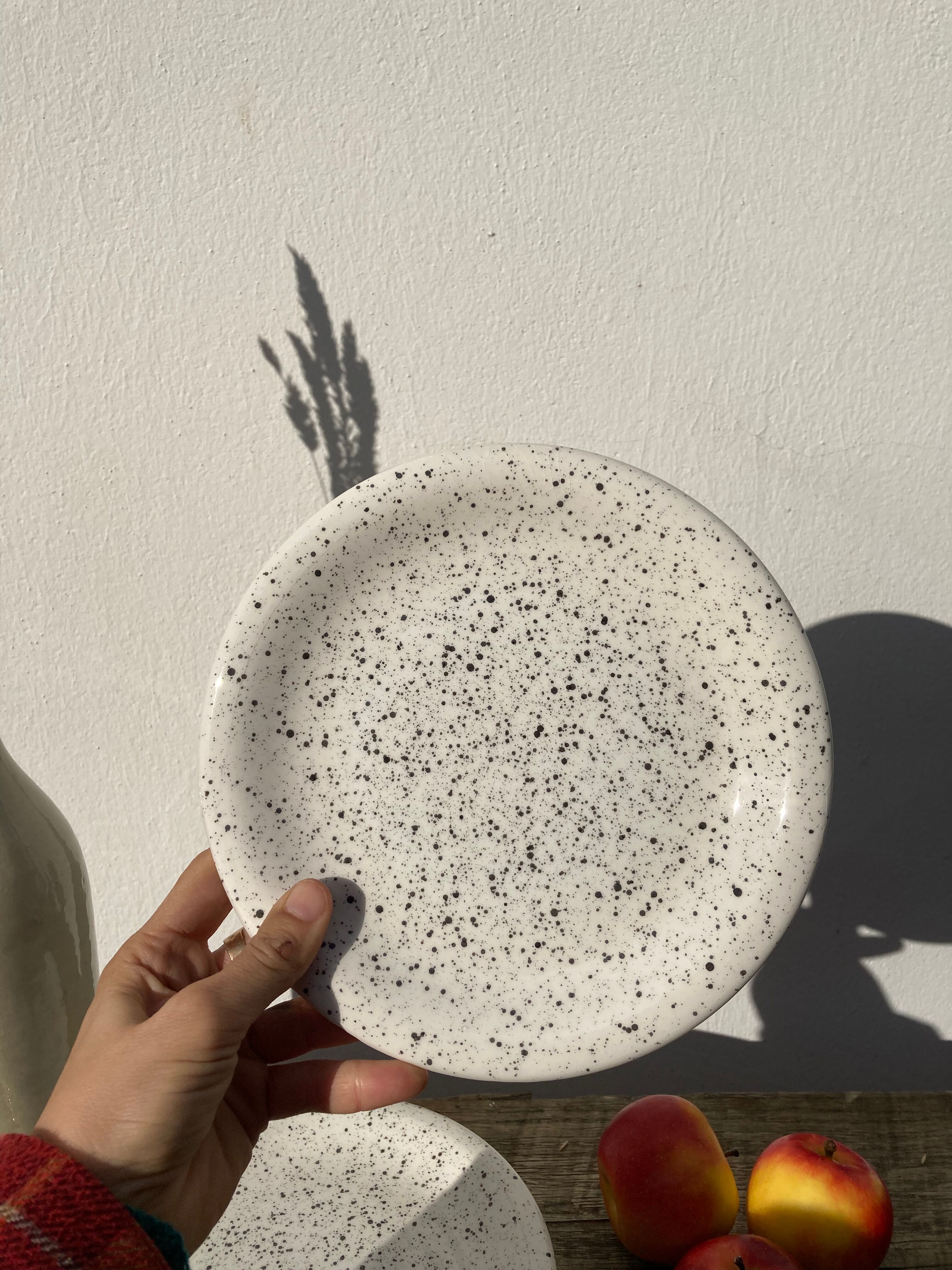 4 black speckled dessert plates on a vintage white background