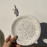 4 black speckled dessert plates on a vintage white background