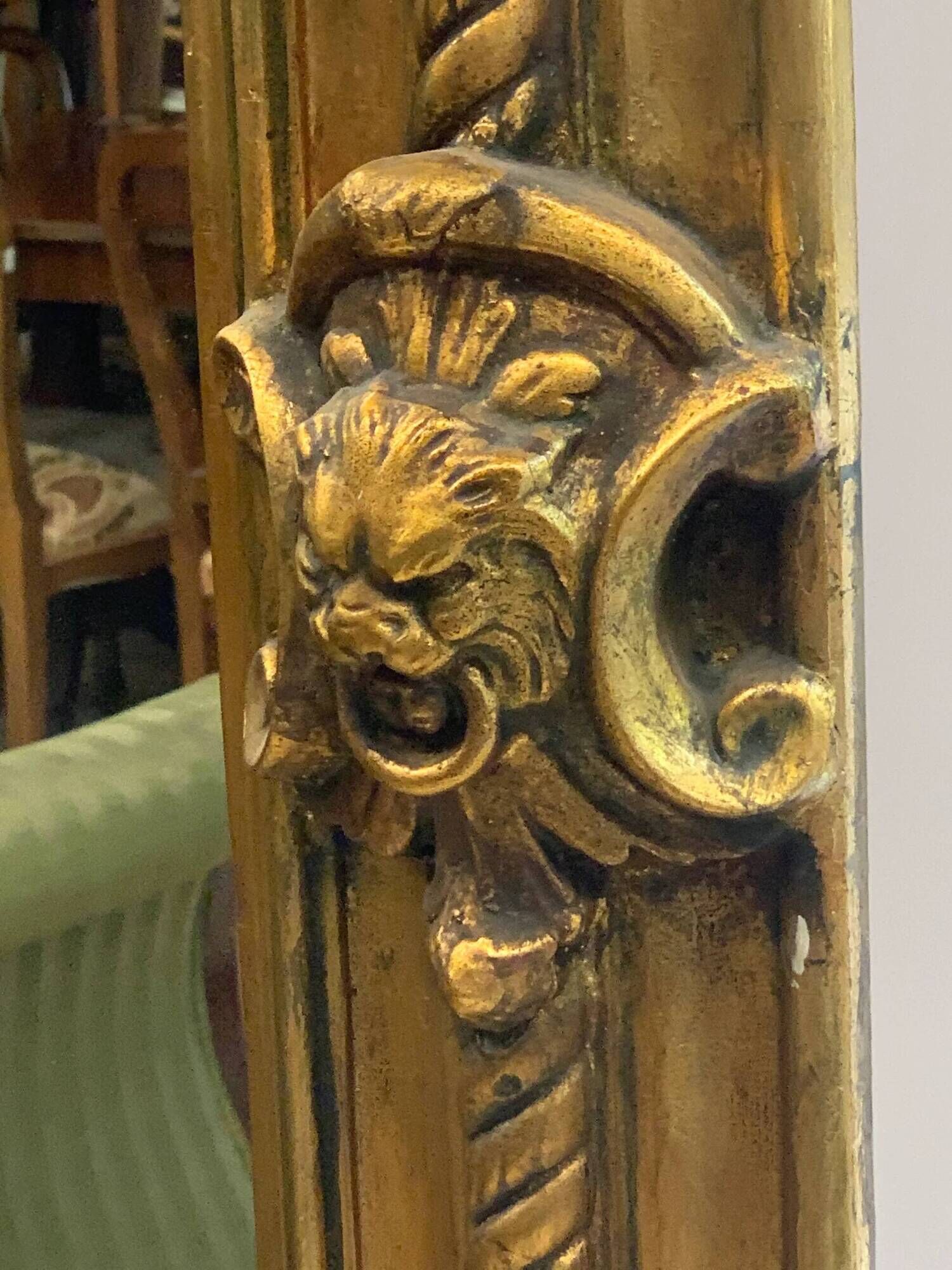 French palace mirror with bow and lion heads, gilded frame.