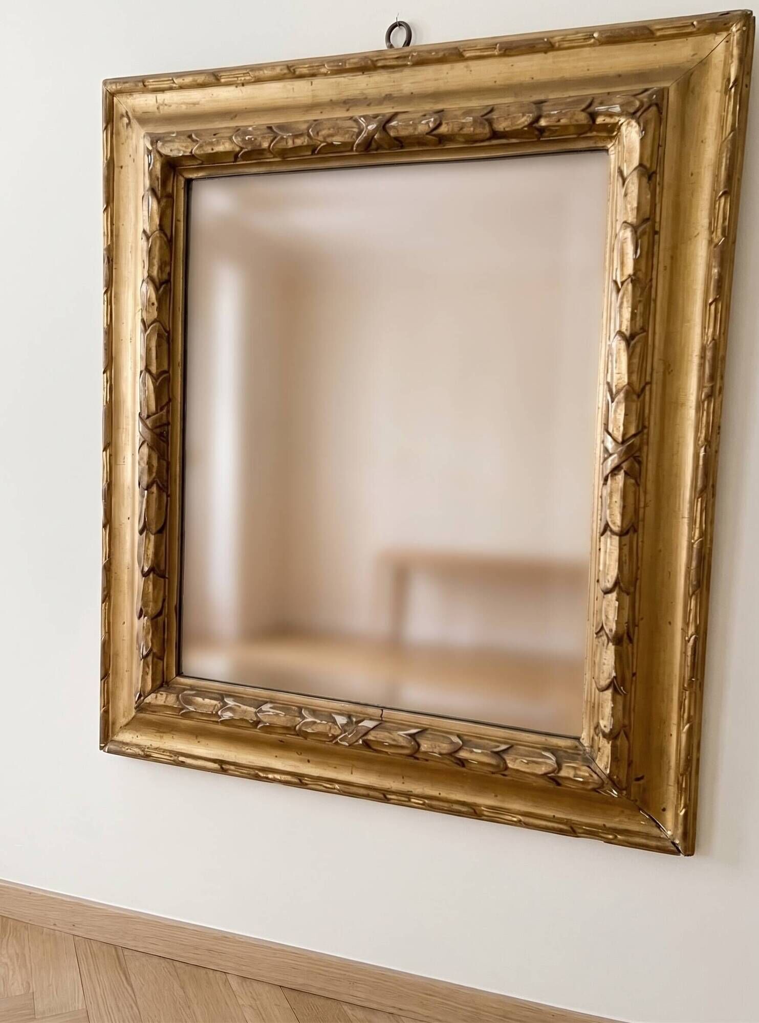 Antique wall mirror with a carved gilded frame featuring leaf motifs.