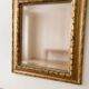 Antique wall mirror with a carved gilded frame featuring leaf motifs.